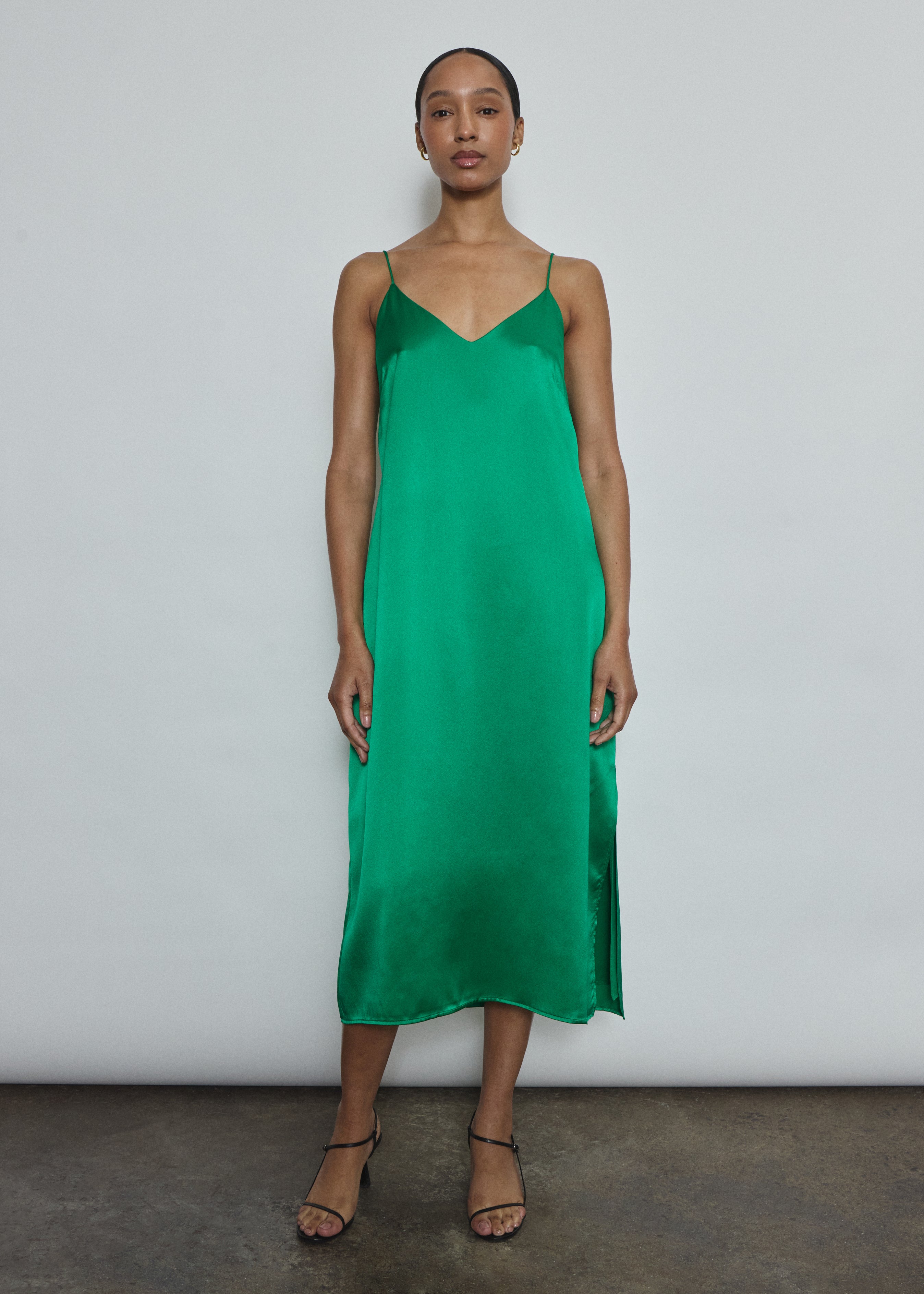 Front view of a model wearing the kelly green silk charmeuse Kamperett Sade Slip Dress, a straight-cut midi with corded straps.