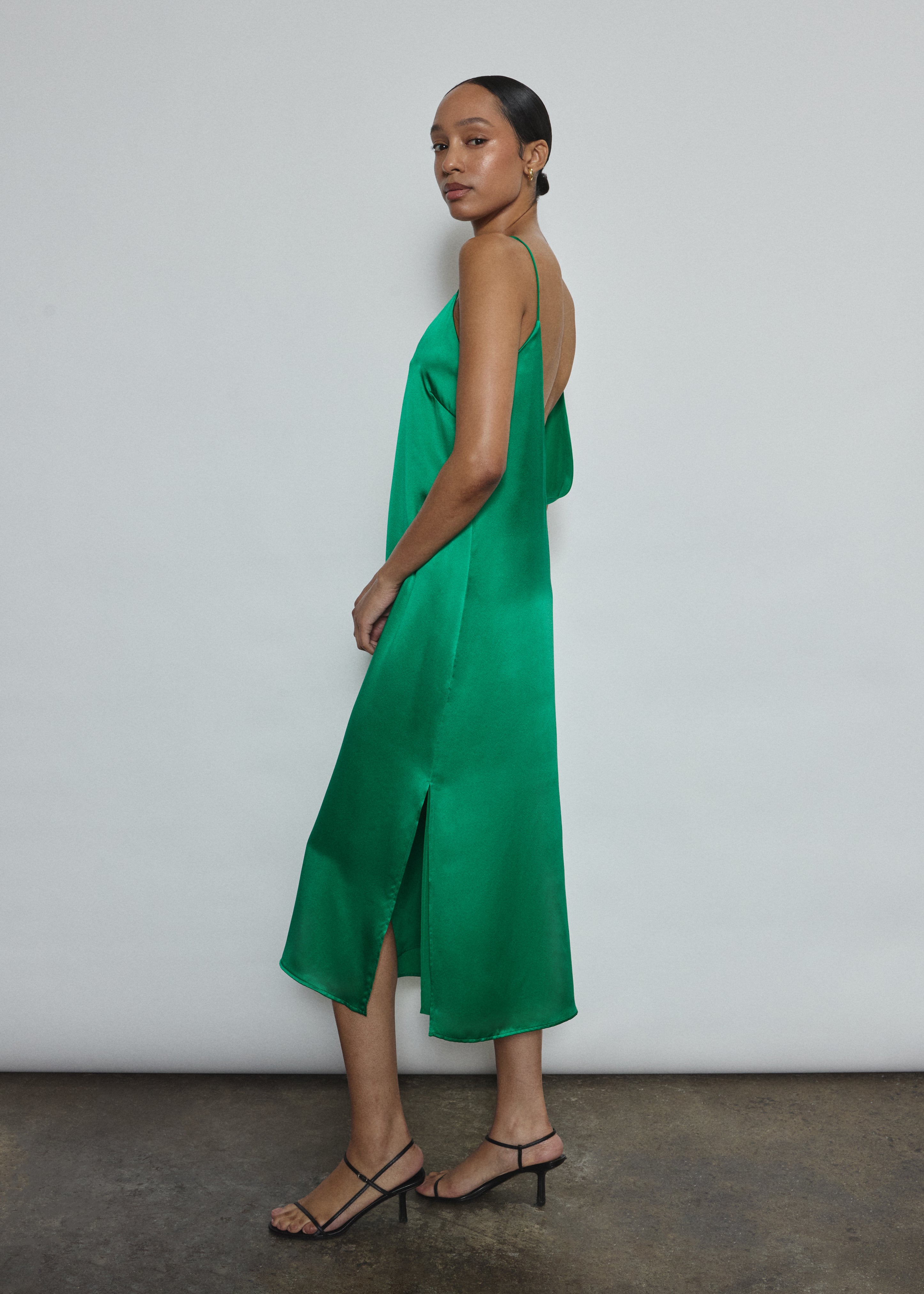 Side view of the kelly green silk charmeuse Kamperett Sade Slip Dress, showing the loose silhouette and midi length.