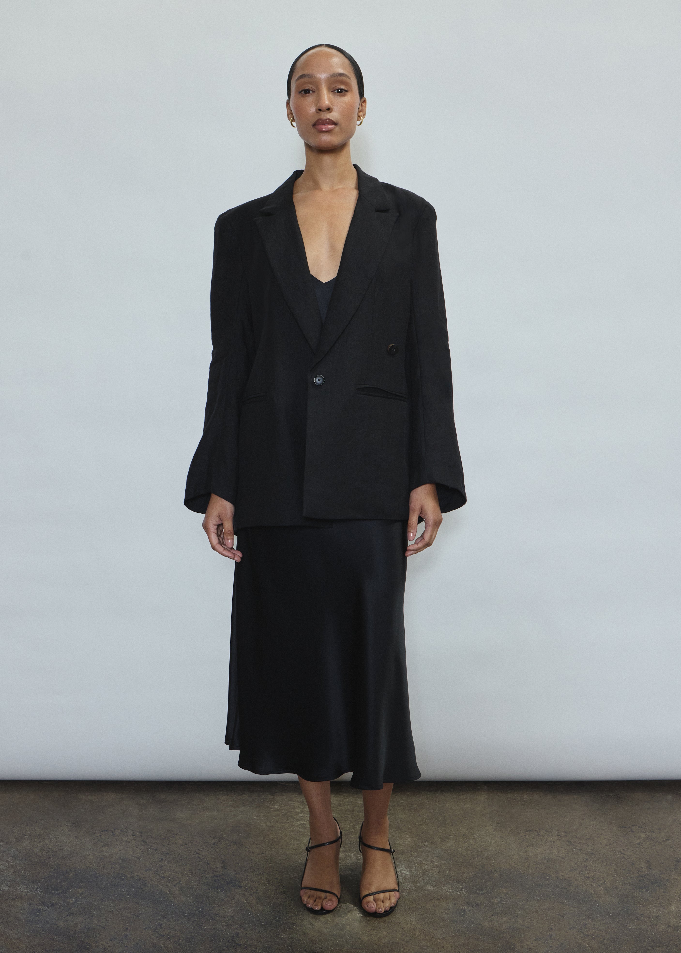Model wearing the black Kamperett Caroline Midi Slip Dress styled with the Orere Linen Blazer.