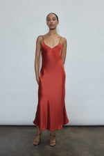Front view of a model wearing the rust sueded silk charmeuse Kamperett Caroline Midi Slip Dress with V-neckline and corded straps.