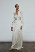 Full-length view of a bride wearing the ivory silk charmeuse Adelaide wrap gown, featuring voluminous sleeves with button cuffs and a plunging neckline.