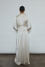 Full-length view of a bride wearing the ivory silk charmeuse Adelaide wrap gown, featuring voluminous sleeves with button cuffs and a plunging neckline.