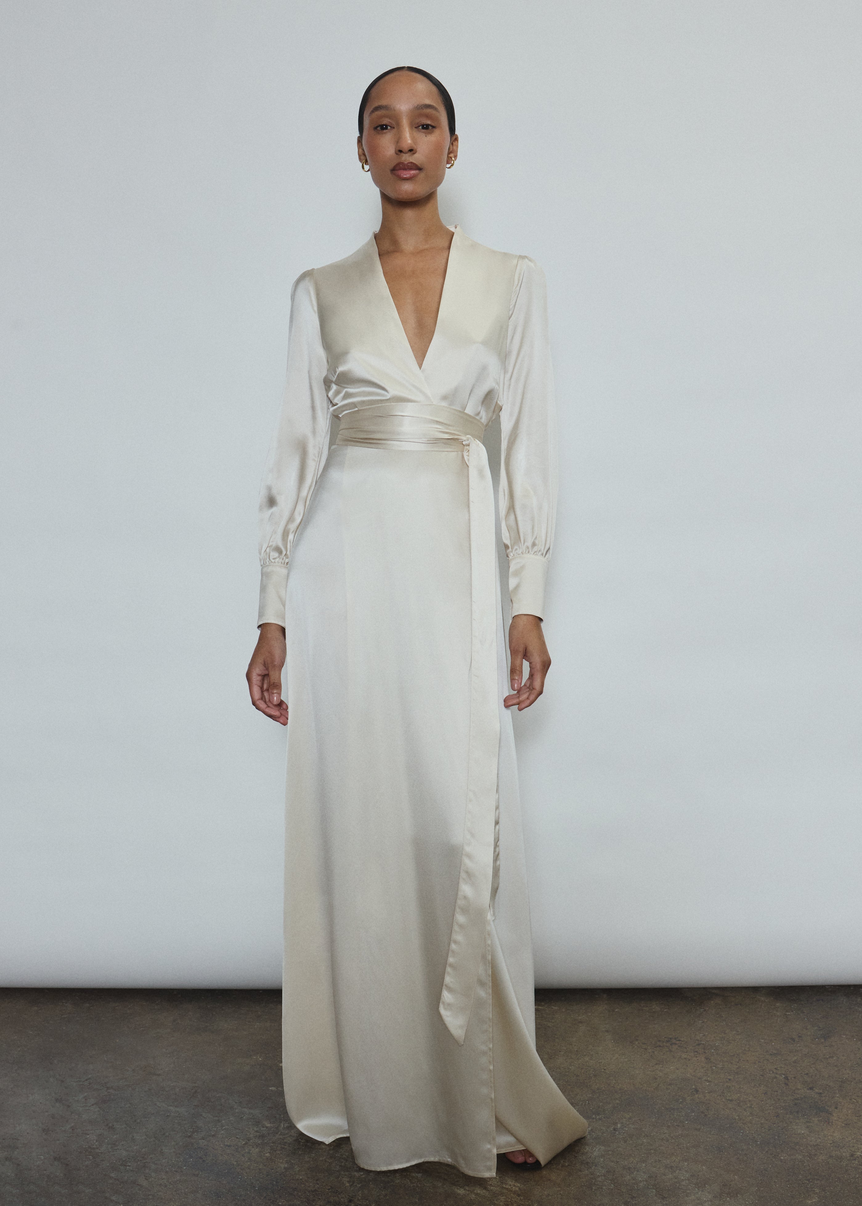 Full-length view of a bride wearing the ivory silk charmeuse Adelaide wrap gown, featuring voluminous sleeves with button cuffs and a plunging neckline.