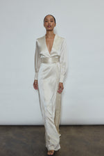Full-length view of a bride wearing the ivory silk charmeuse Adelaide wrap gown, featuring voluminous sleeves with button cuffs and a plunging neckline.
