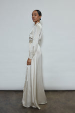 Full-length view of a bride wearing the ivory silk charmeuse Adelaide wrap gown, featuring voluminous sleeves with button cuffs and a plunging neckline.