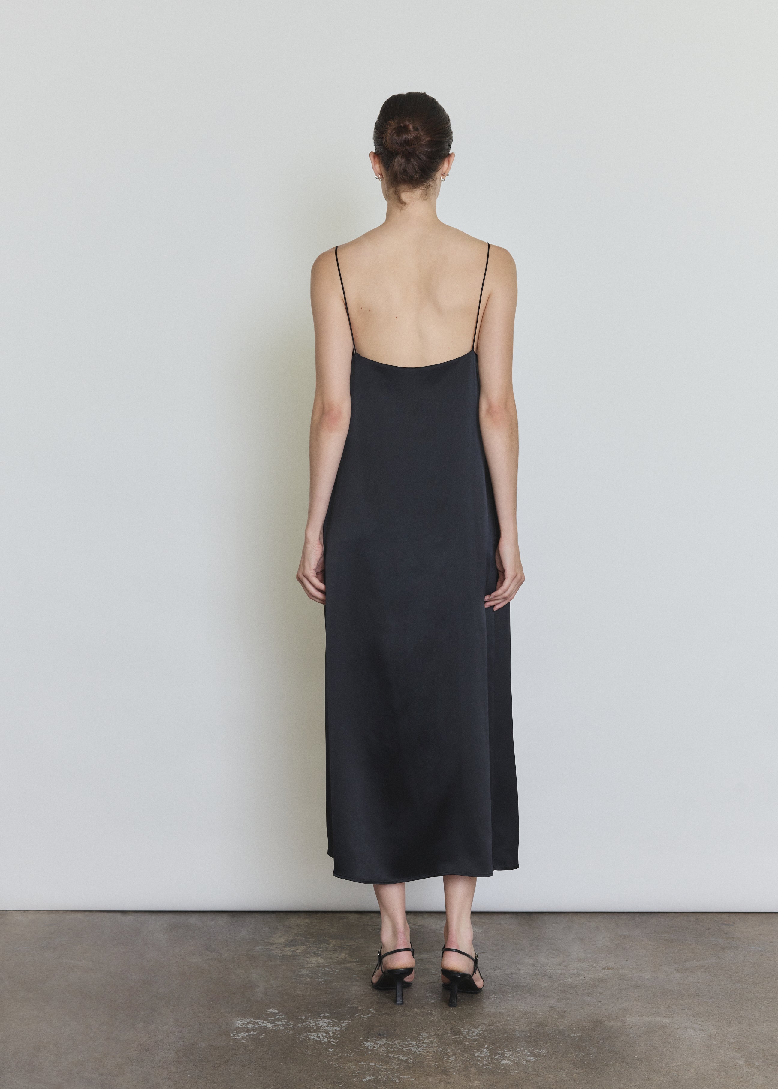 Back view of the black silk charmeuse Kamperett Agnes Slip Dress with straight-cut back and corded straps.