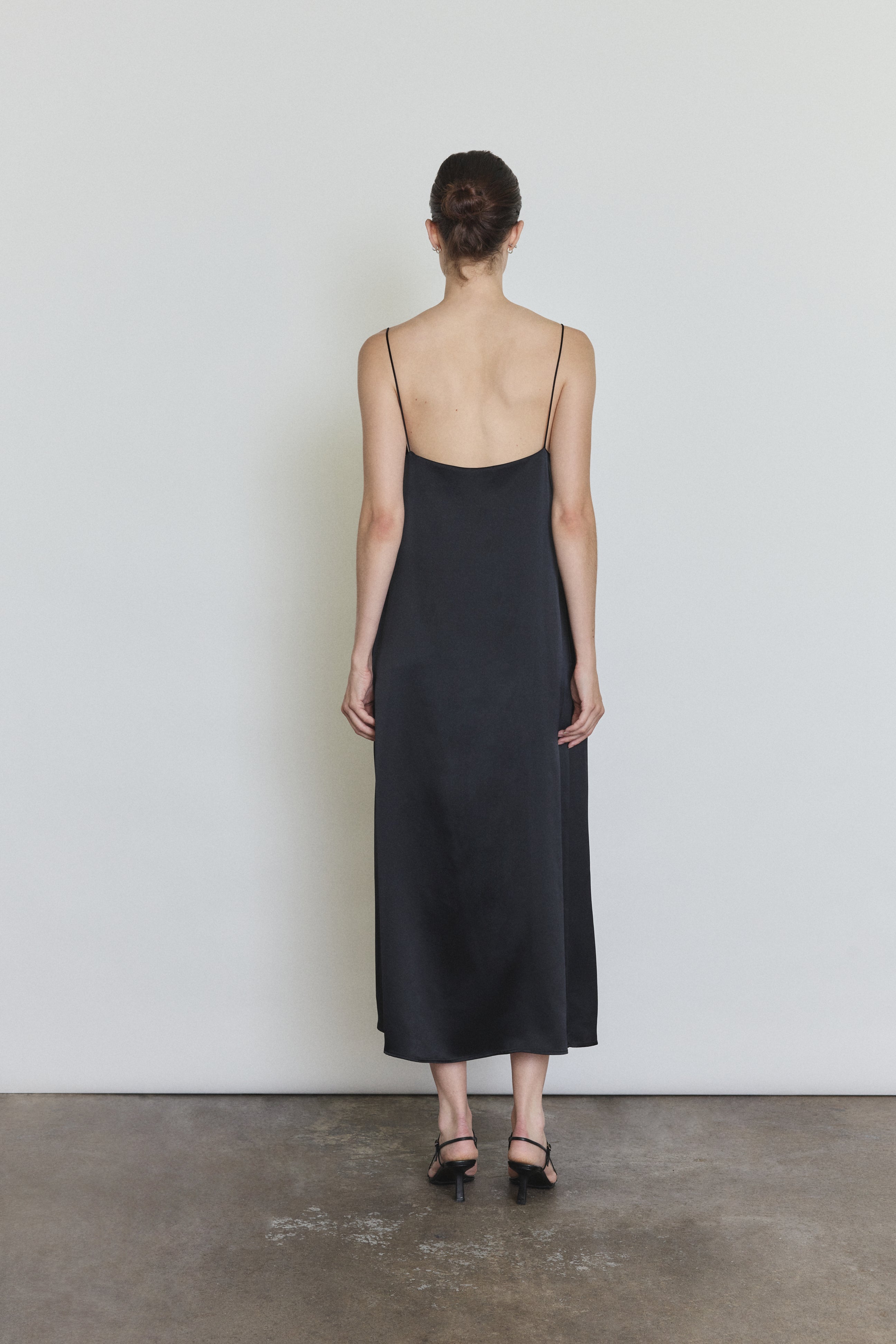 Back view of the black silk charmeuse Kamperett Agnes Slip Dress with straight-cut back and corded straps.