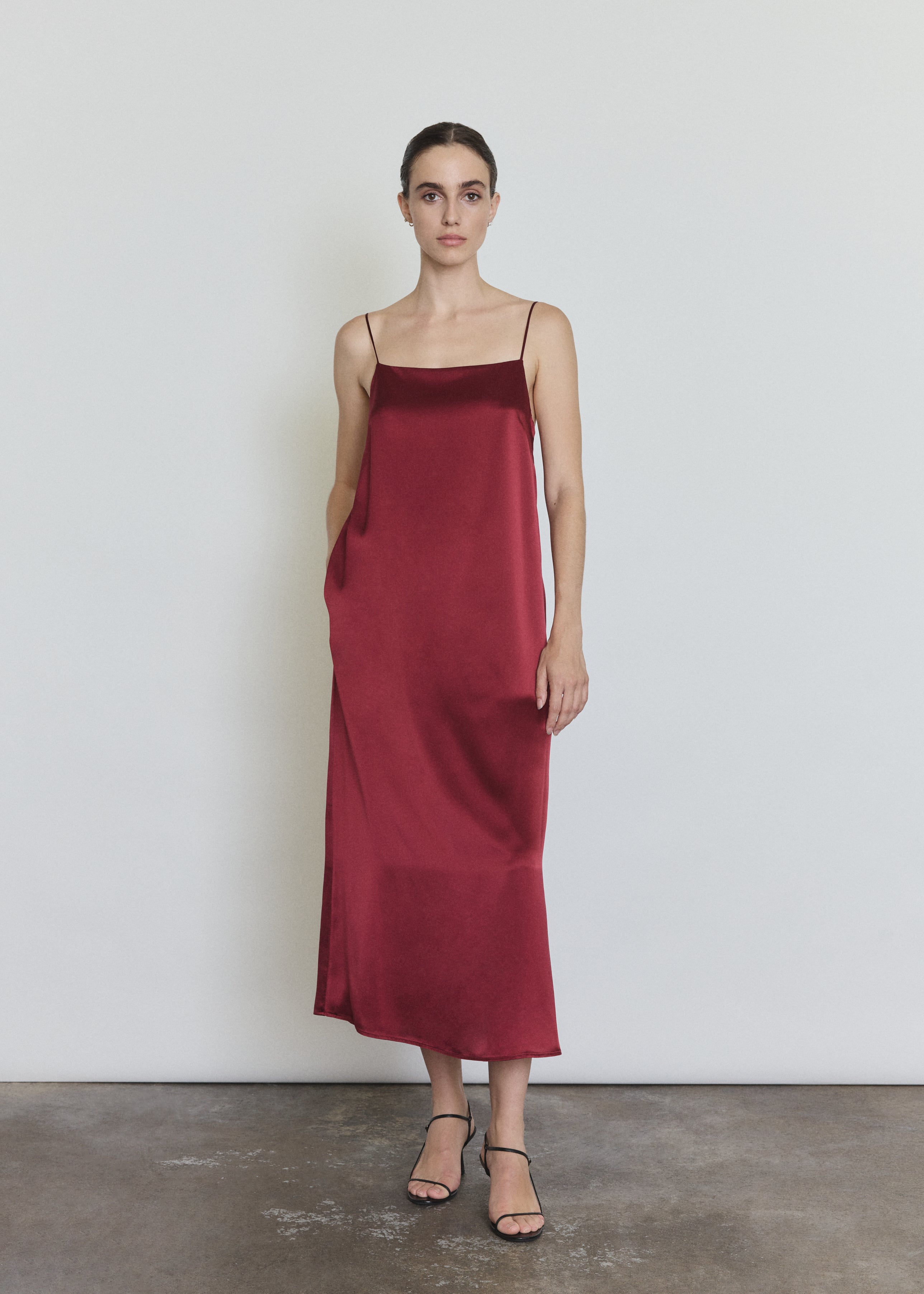 Front view of a model wearing the bordeaux silk charmeuse Kamperett Agnes Slip Dress, a boxy midi slip with straight neckline and corded straps.
