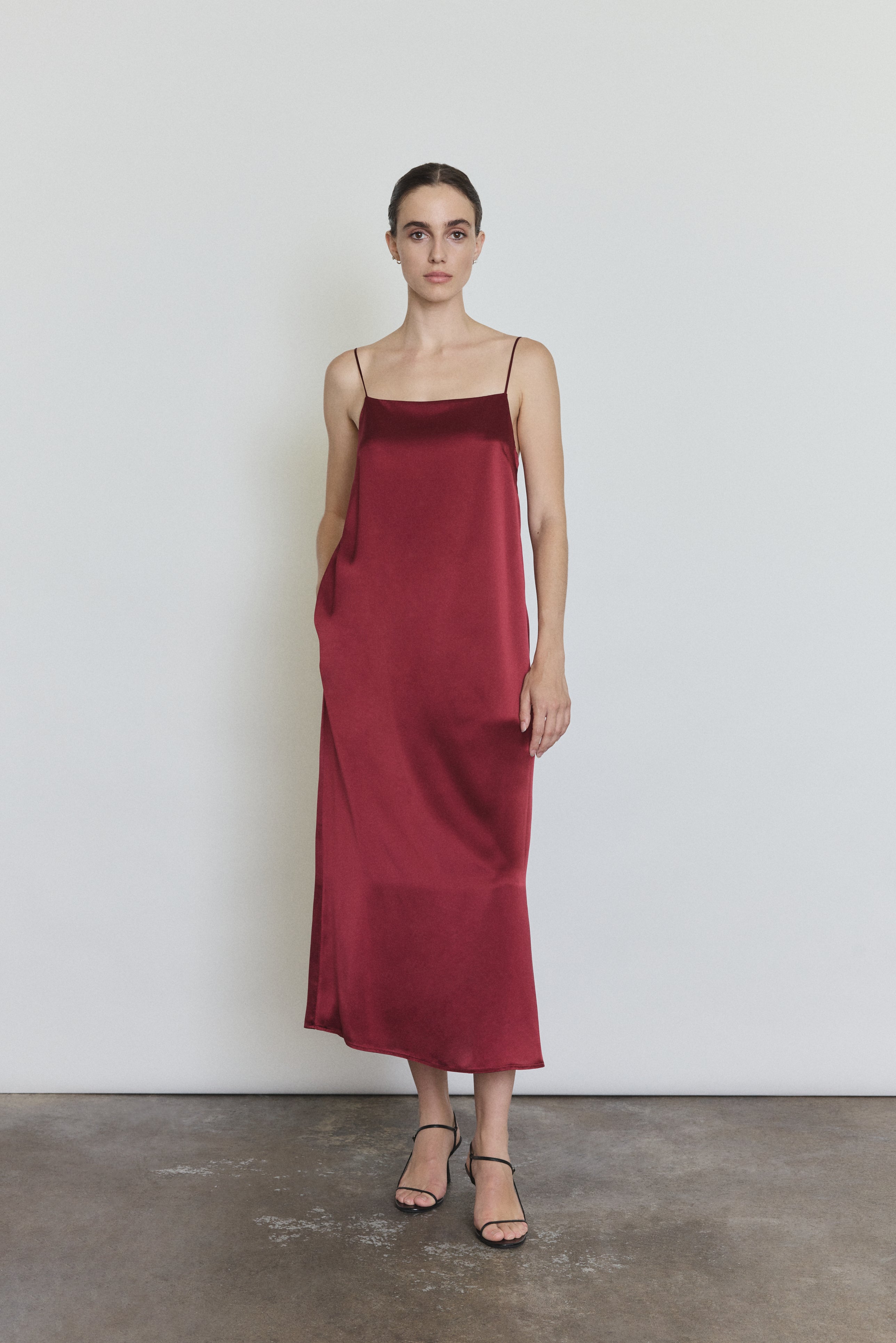 Front view of a model wearing the bordeaux silk charmeuse Kamperett Agnes Slip Dress, a boxy midi slip with straight neckline and corded straps.