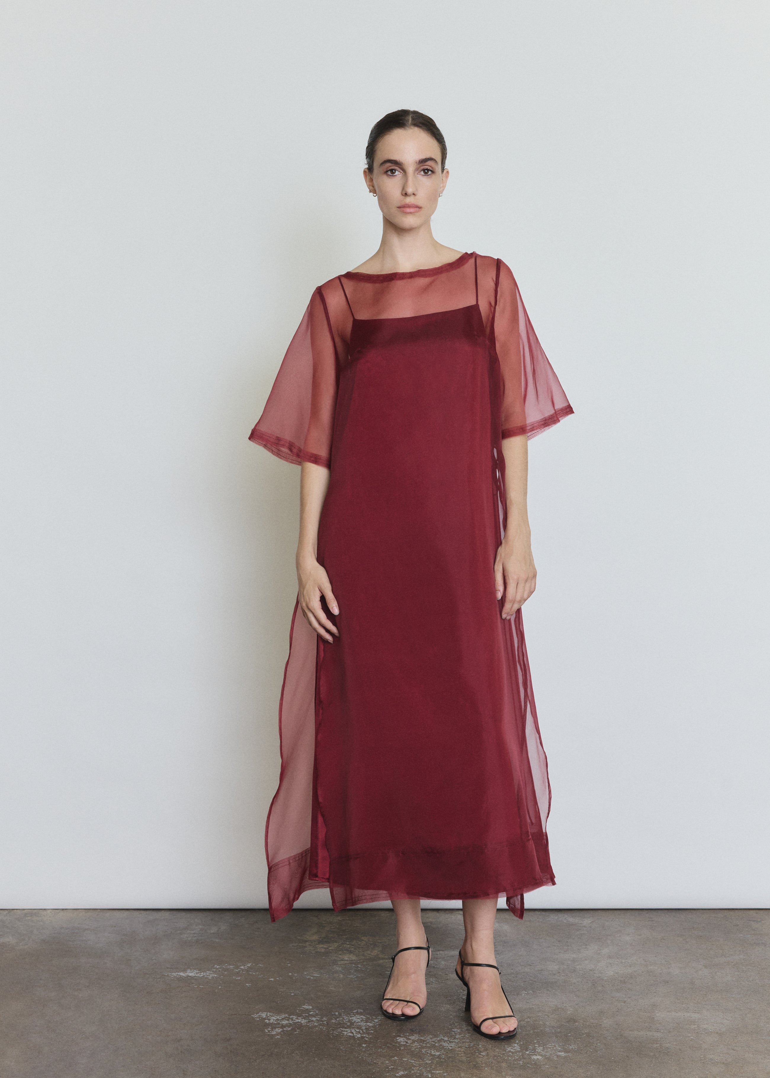 Model wearing the bordeaux Kamperett Agnes Slip Dress layered under the Thea Sheath Dress in Bordeaux.