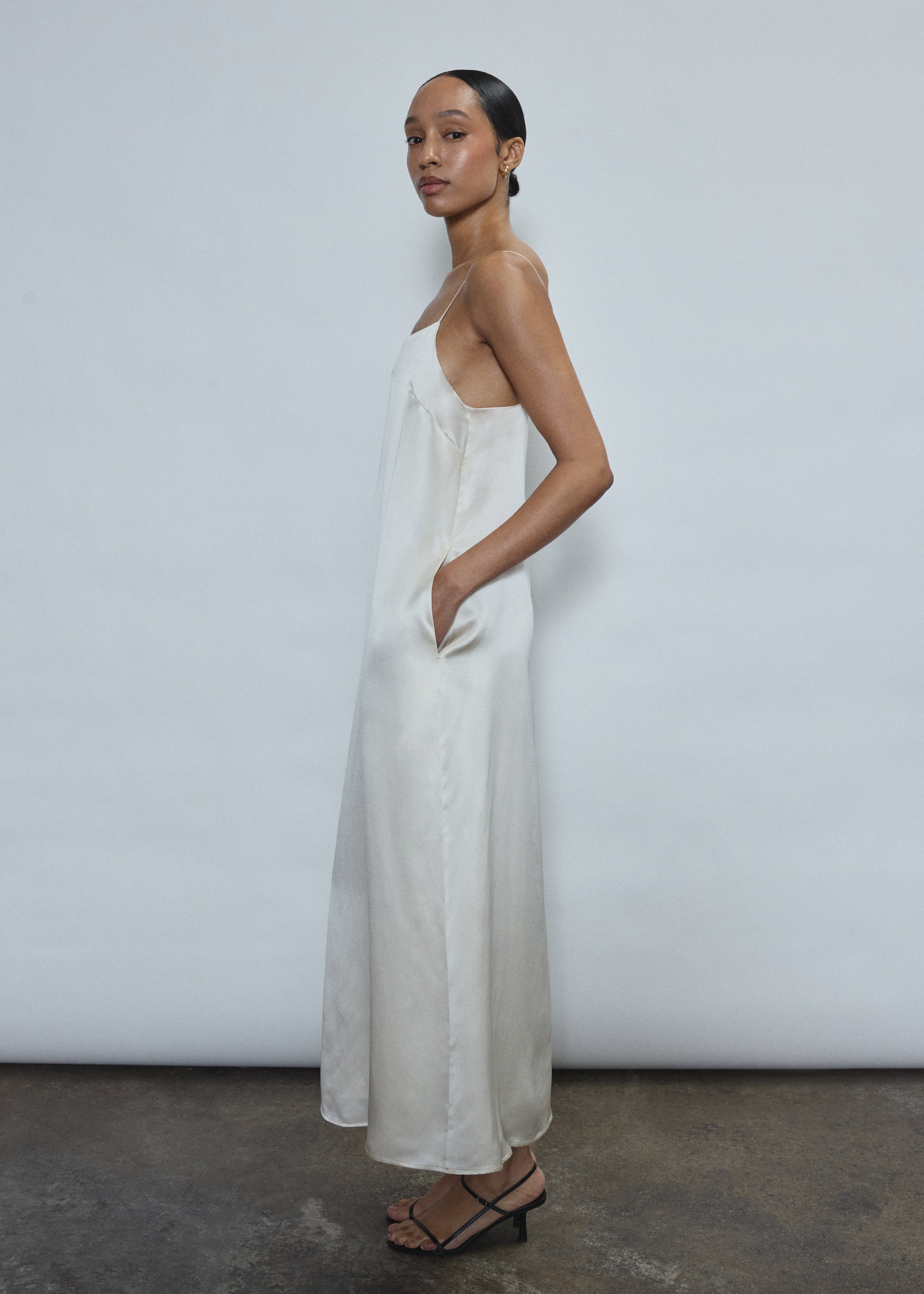 Side view of the ivory silk charmeuse Kamperett Agnes Slip Dress showing the loose midi silhouette and corded straps.