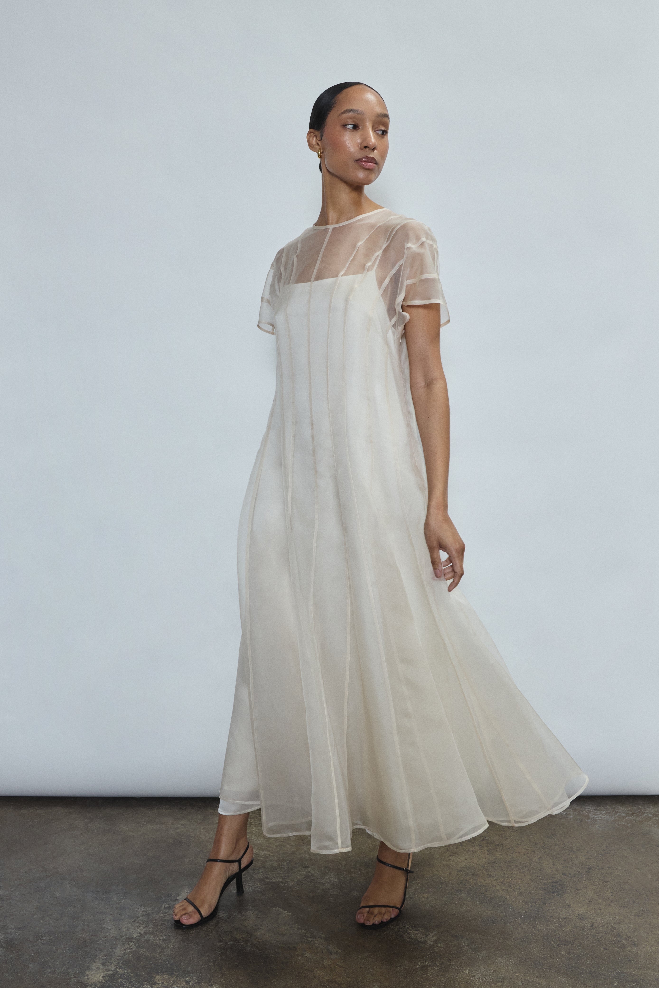 Editorial image of the ivory Kamperett Agnes Slip Dress layered under the Anemoia Midi Dress, a modern bridal styling.