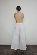 Model wearing the Kamperett Alix Pant in White, featuring a high-waisted wide-leg silhouette in crisp Japanese cotton lawn with deep side pockets.