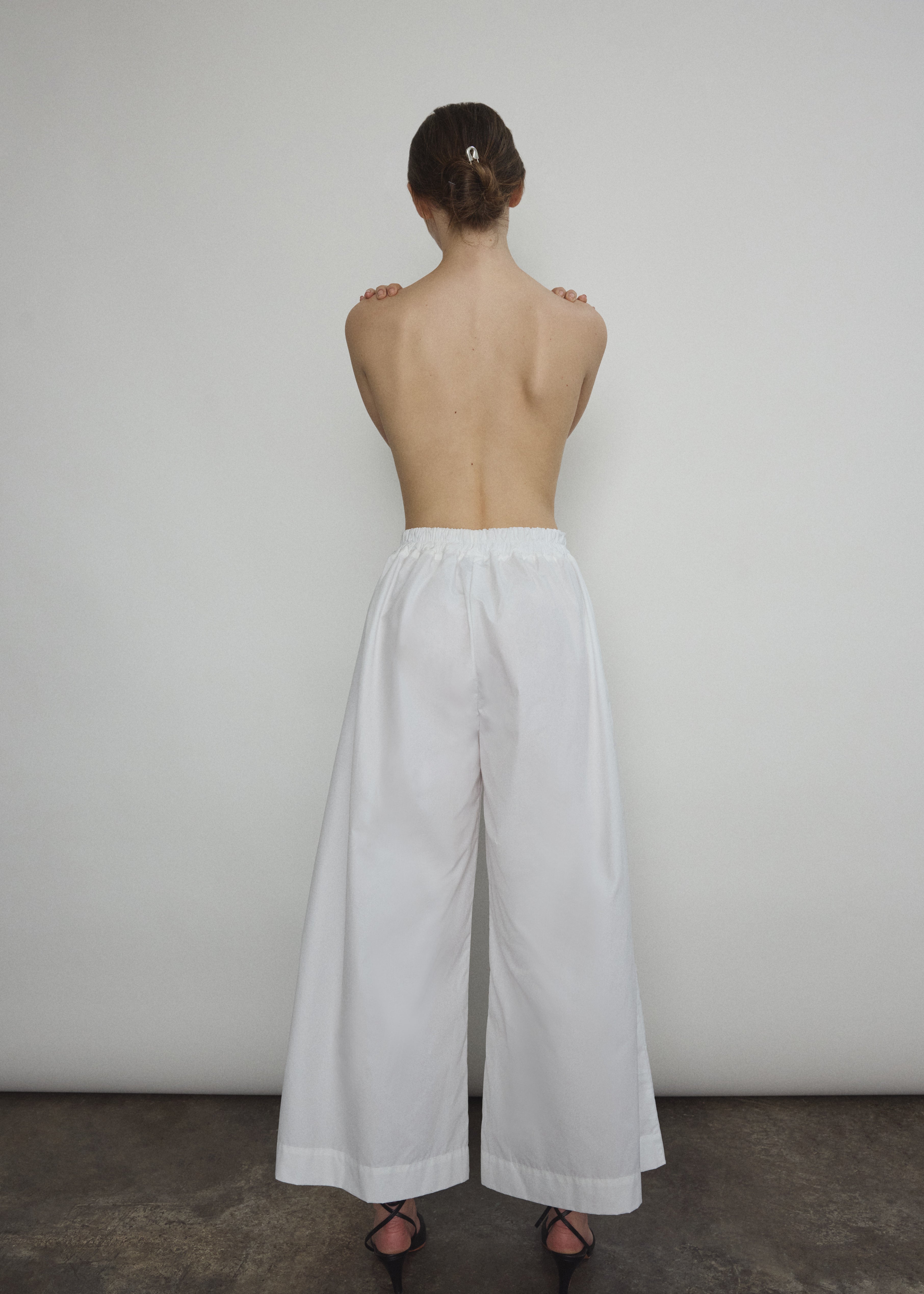 Model wearing the Kamperett Alix Pant in White, featuring a high-waisted wide-leg silhouette in crisp Japanese cotton lawn with deep side pockets.