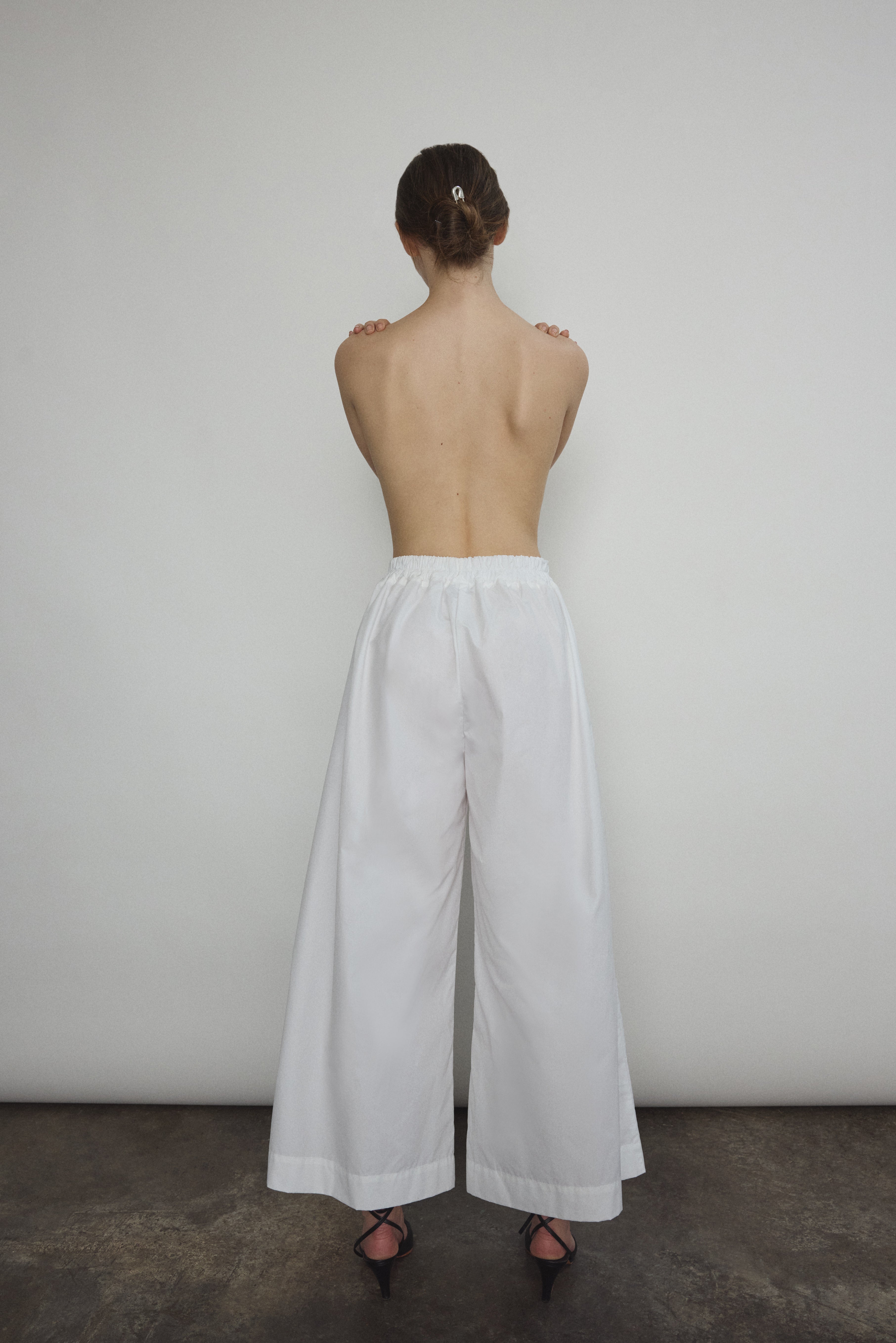 Model wearing the Kamperett Alix Pant in White, featuring a high-waisted wide-leg silhouette in crisp Japanese cotton lawn with deep side pockets.