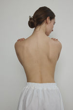 Model wearing the Kamperett Alix Pant in White, featuring a high-waisted wide-leg silhouette in crisp Japanese cotton lawn with deep side pockets.