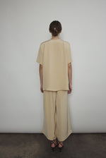 Model wearing the Kamperett Alix Pant in Beige silk crepe, featuring a high-waisted wide-leg fit and a sophisticated fluid drape.