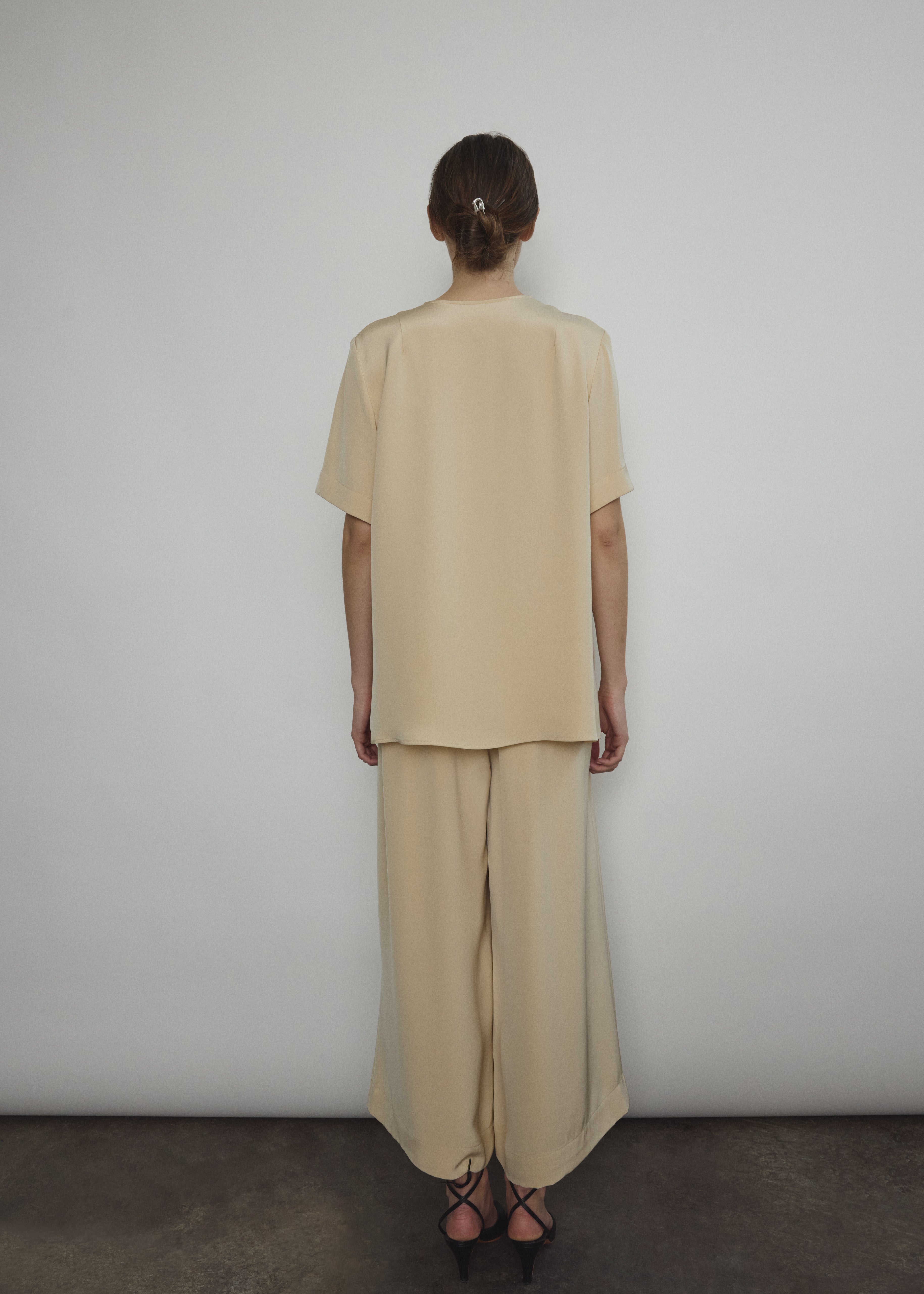 Model wearing the Kamperett Alix Pant in Beige silk crepe, featuring a high-waisted wide-leg fit and a sophisticated fluid drape.