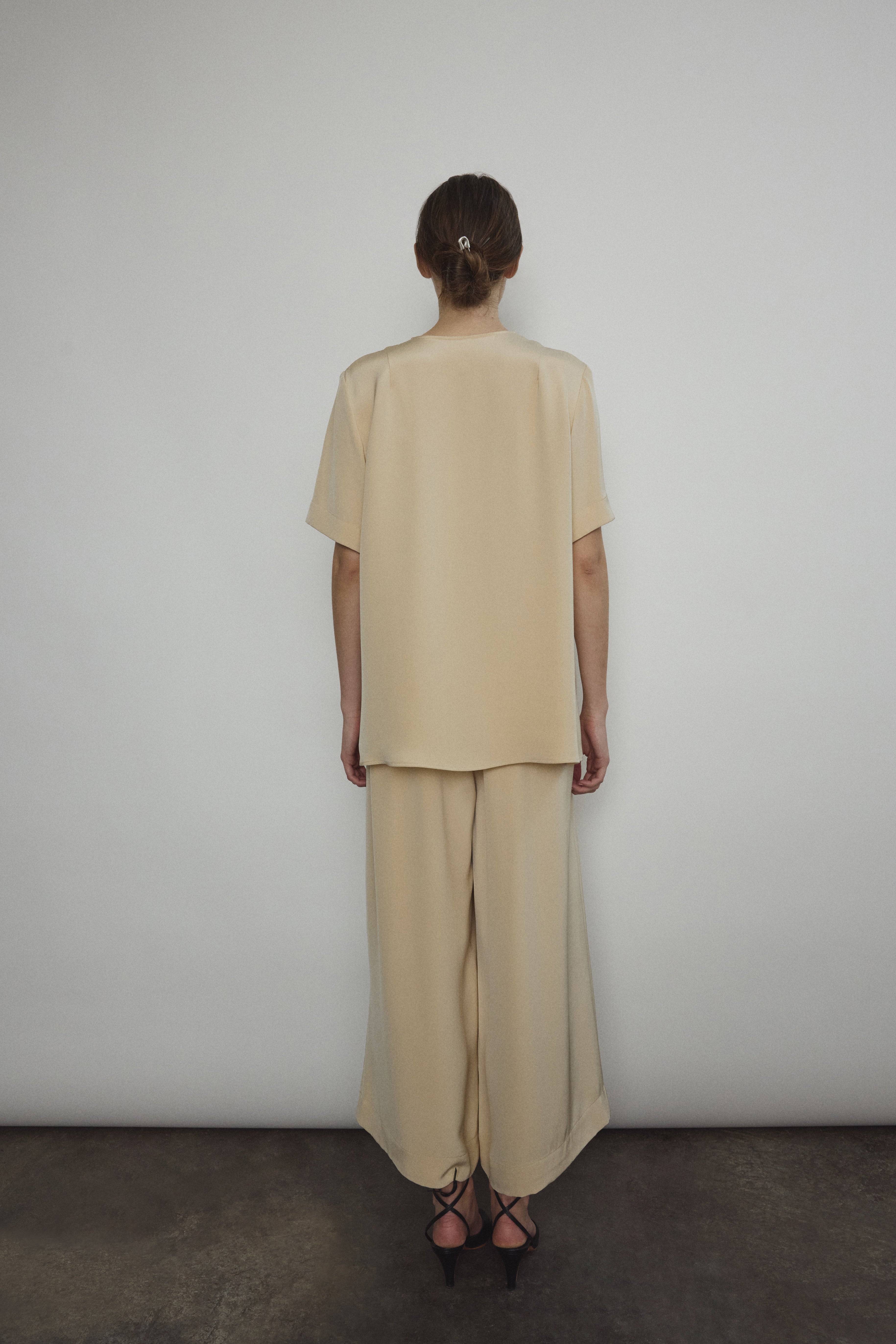 Model wearing the Kamperett Alix Pant in Beige silk crepe, featuring a high-waisted wide-leg fit and a sophisticated fluid drape.