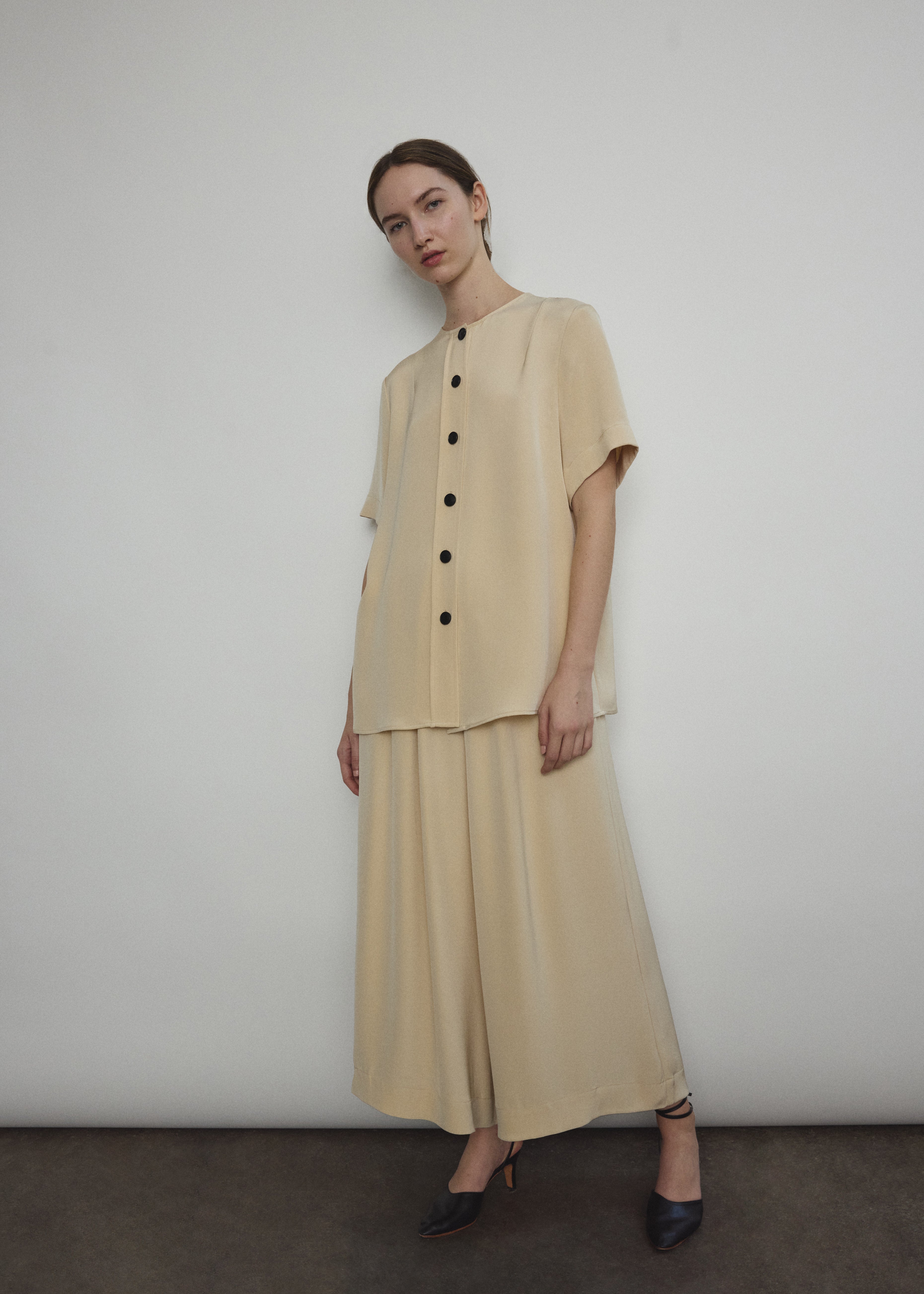 Model wearing the Kamperett Alix Pant in Beige silk crepe, featuring a high-waisted wide-leg fit and a sophisticated fluid drape.