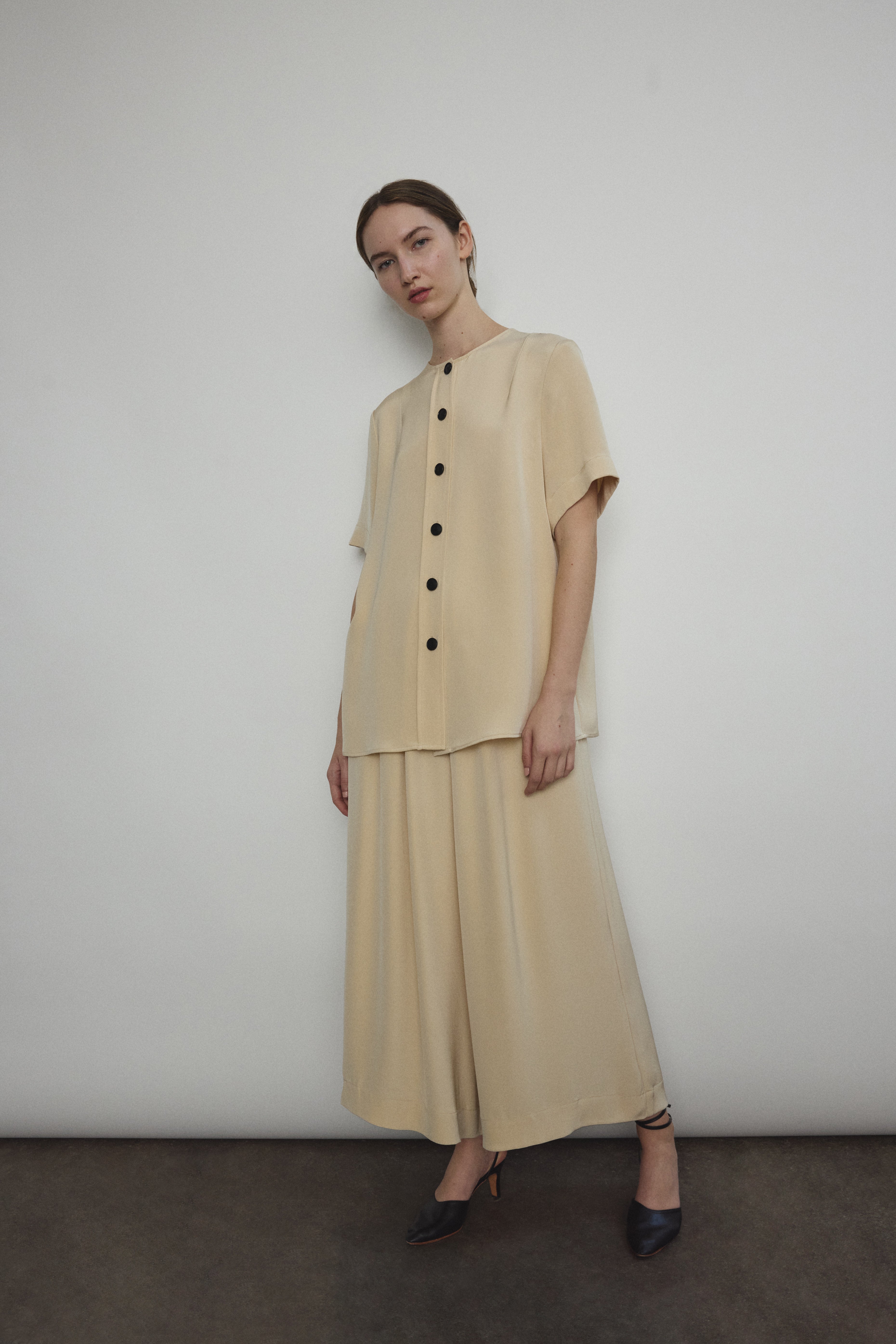 Model wearing the Kamperett Alix Pant in Beige silk crepe, featuring a high-waisted wide-leg fit and a sophisticated fluid drape.