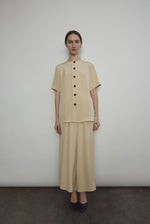Model wearing the Kamperett Alix Pant in Beige silk crepe, featuring a high-waisted wide-leg fit and a sophisticated fluid drape.