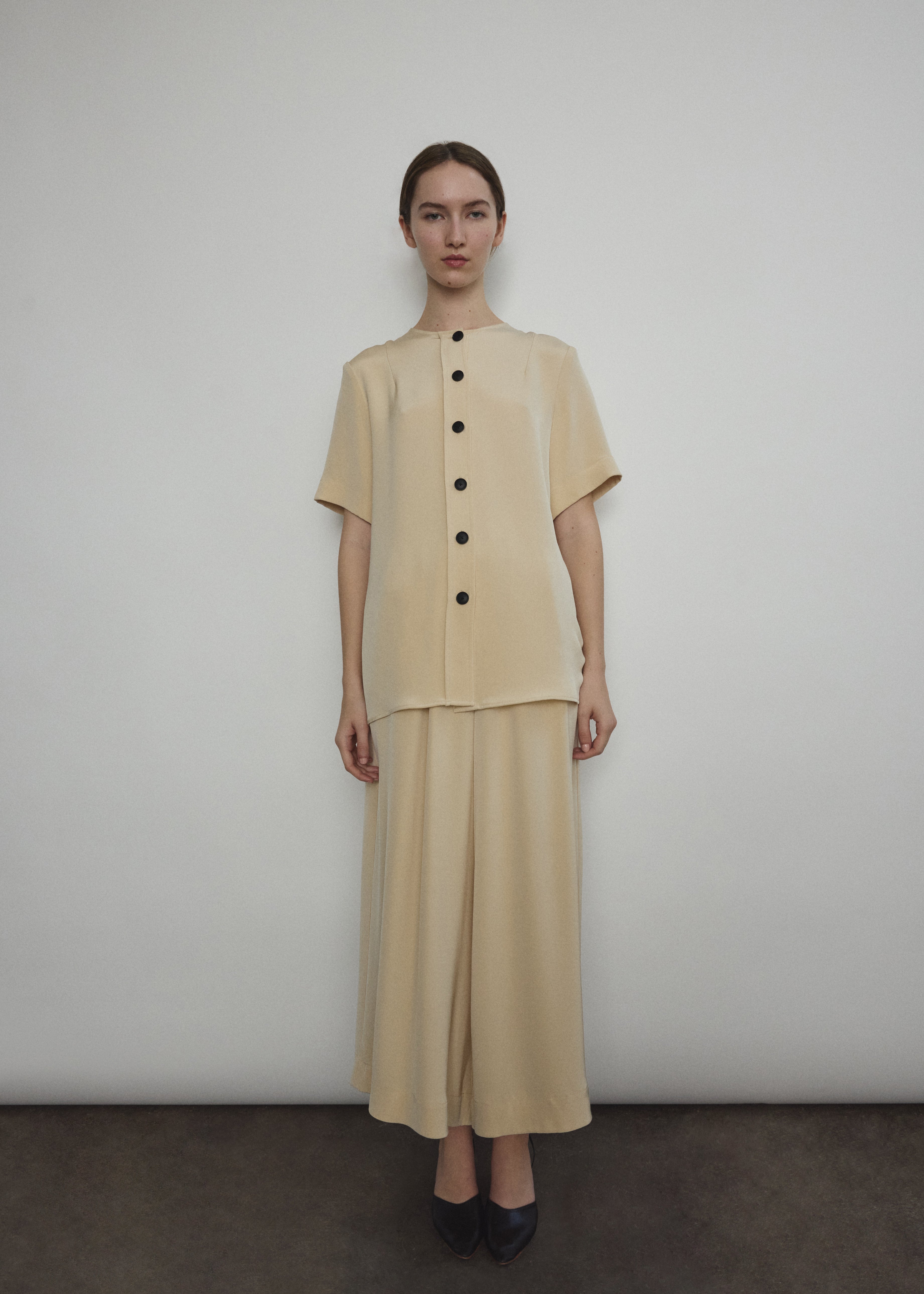 Model wearing the Kamperett Alix Pant in Beige silk crepe, featuring a high-waisted wide-leg fit and a sophisticated fluid drape.
