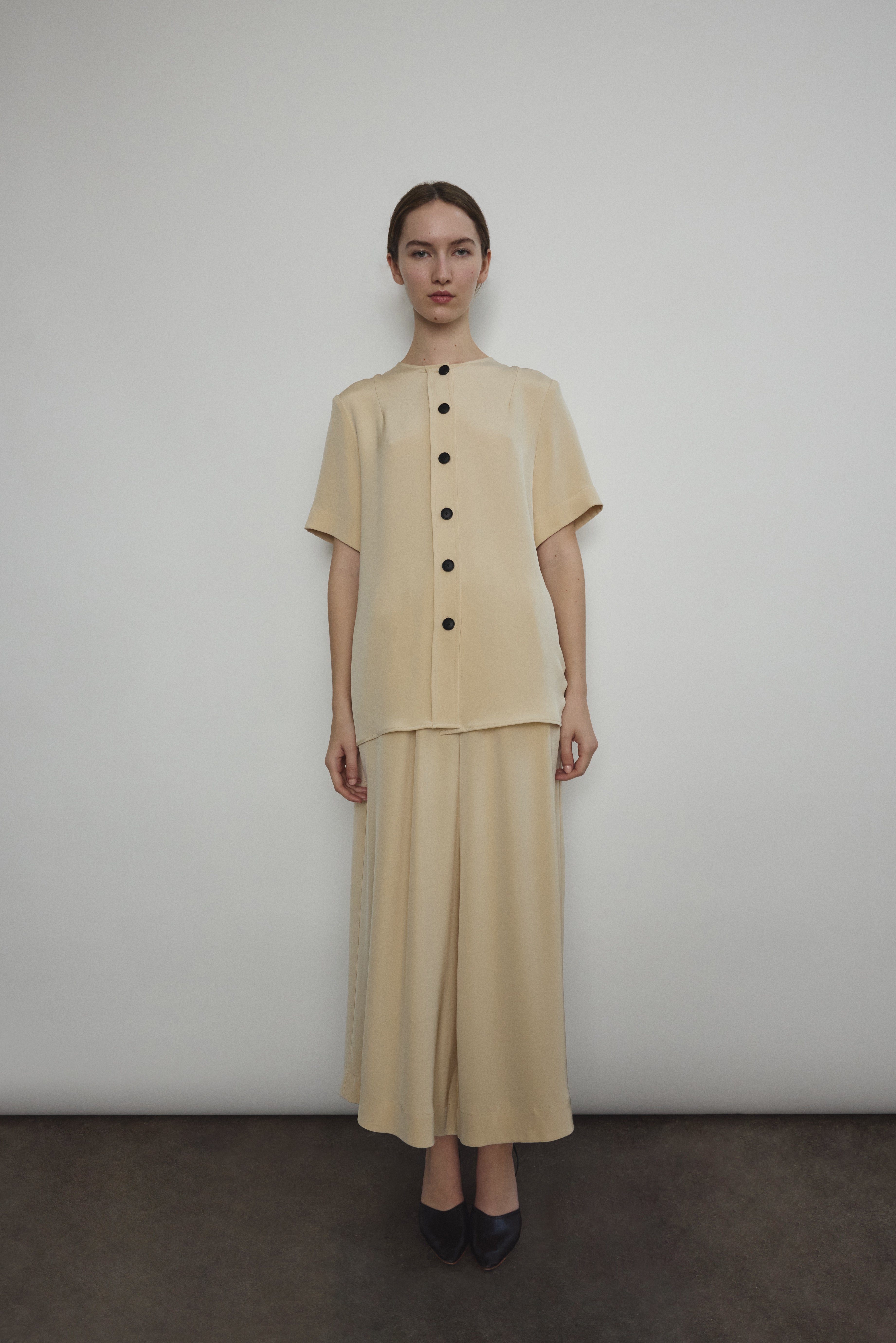 Model wearing the Kamperett Alix Pant in Beige silk crepe, featuring a high-waisted wide-leg fit and a sophisticated fluid drape.