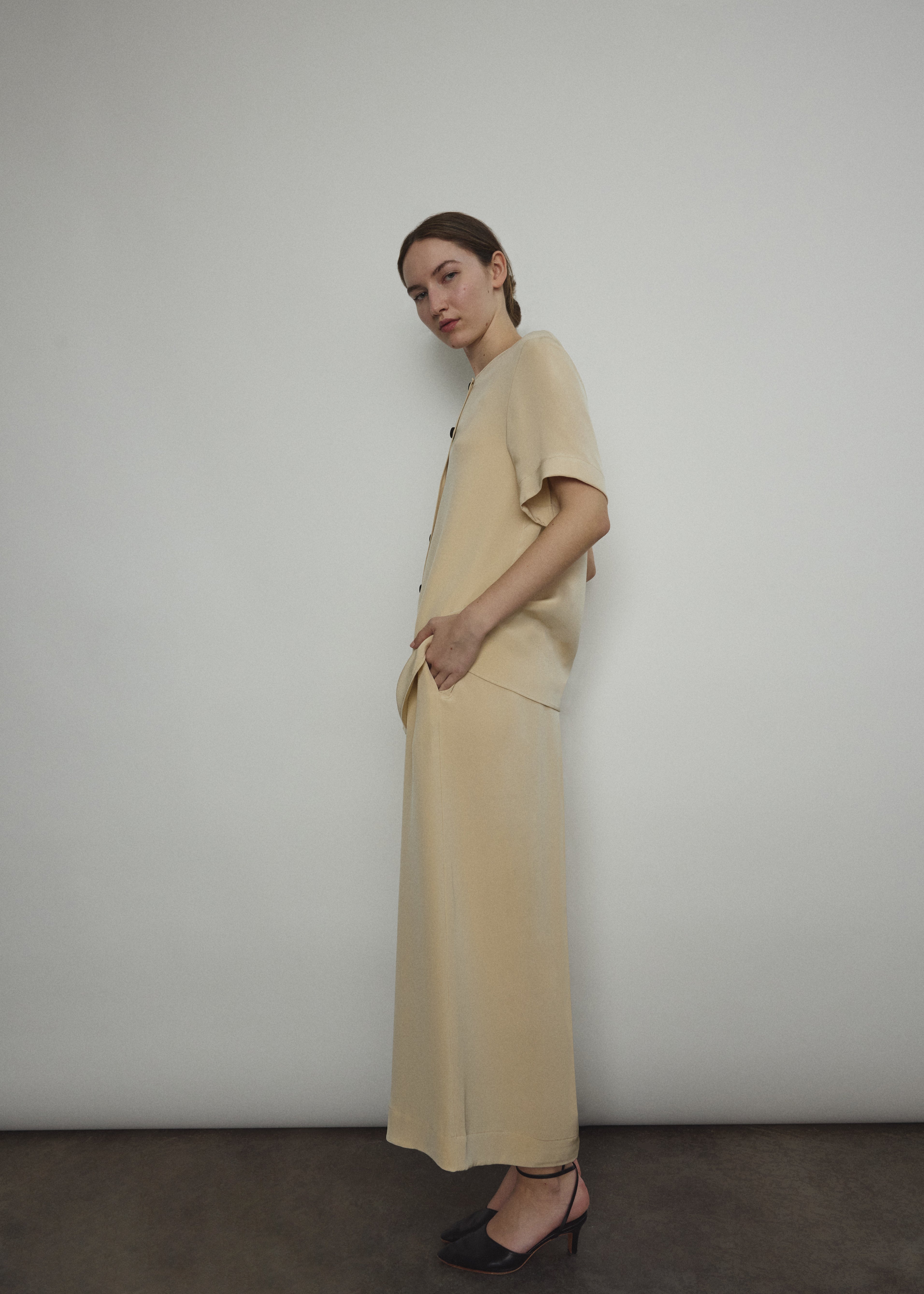Model wearing the Kamperett Alix Pant in Beige silk crepe, featuring a high-waisted wide-leg fit and a sophisticated fluid drape.