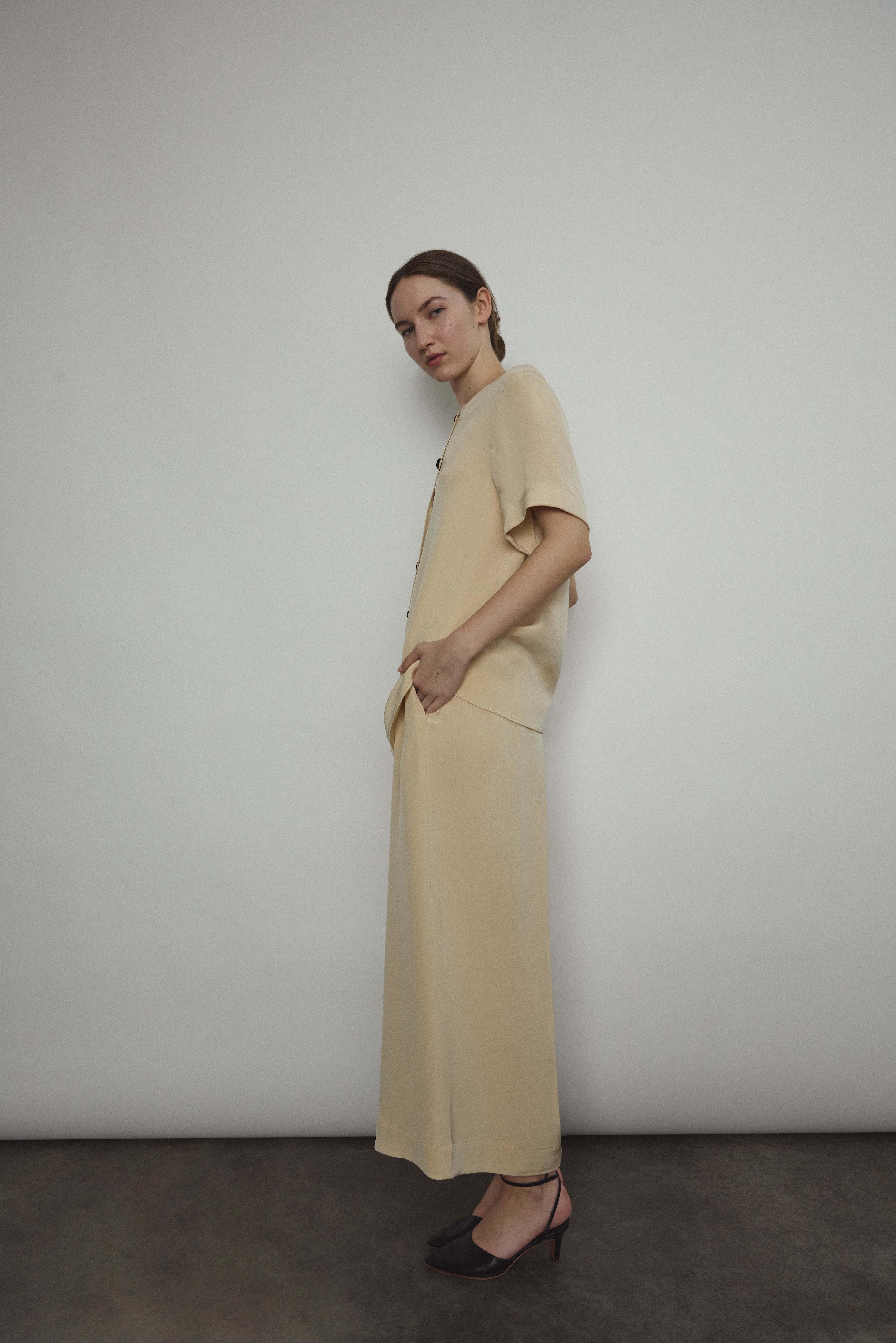 Model wearing the Kamperett Alix Pant in Beige silk crepe, featuring a high-waisted wide-leg fit and a sophisticated fluid drape.