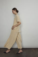 Model wearing the Kamperett Alix Pant in Beige silk crepe, featuring a high-waisted wide-leg fit and a sophisticated fluid drape.