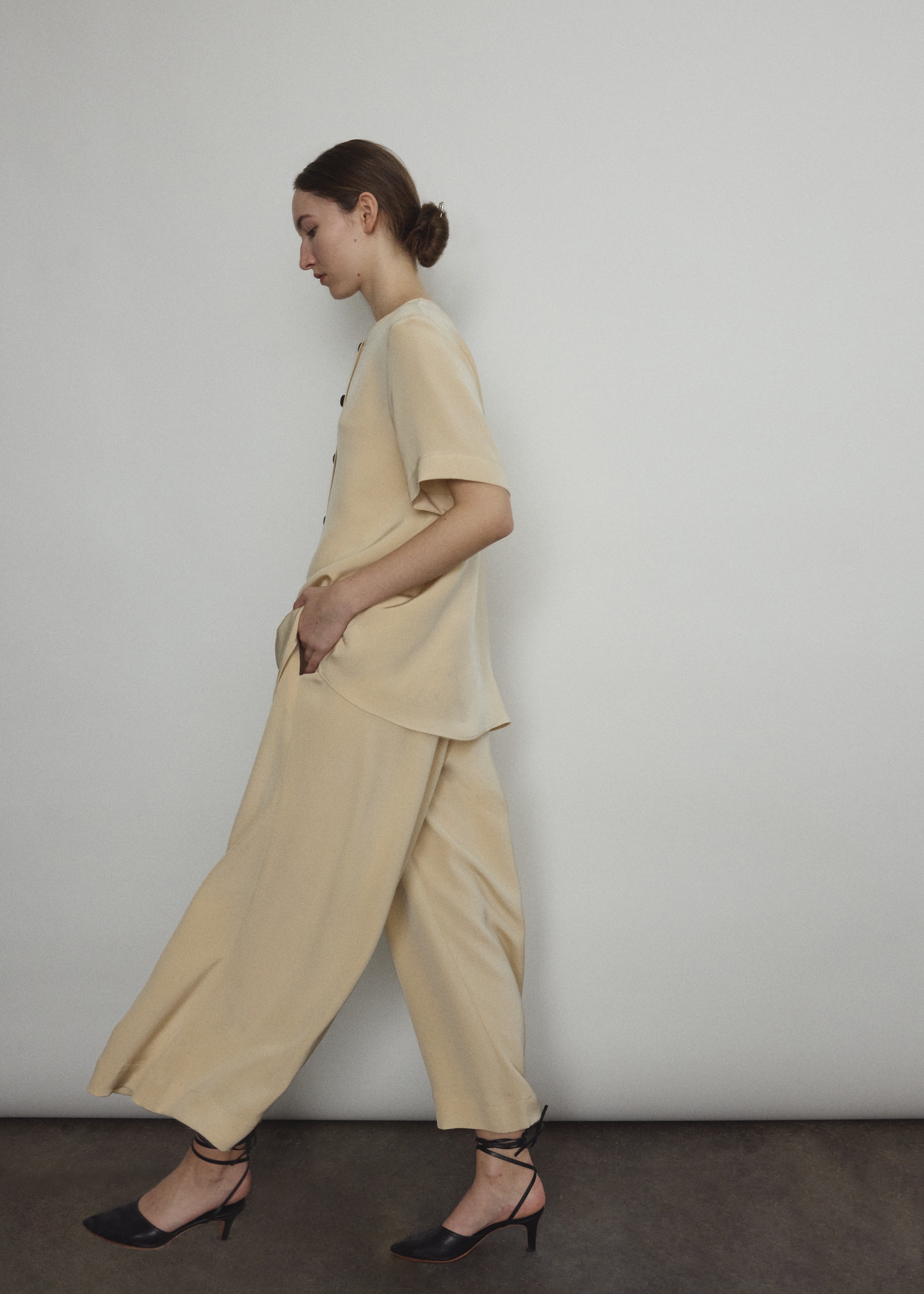 Model wearing the Kamperett Alix Pant in Beige silk crepe, featuring a high-waisted wide-leg fit and a sophisticated fluid drape.