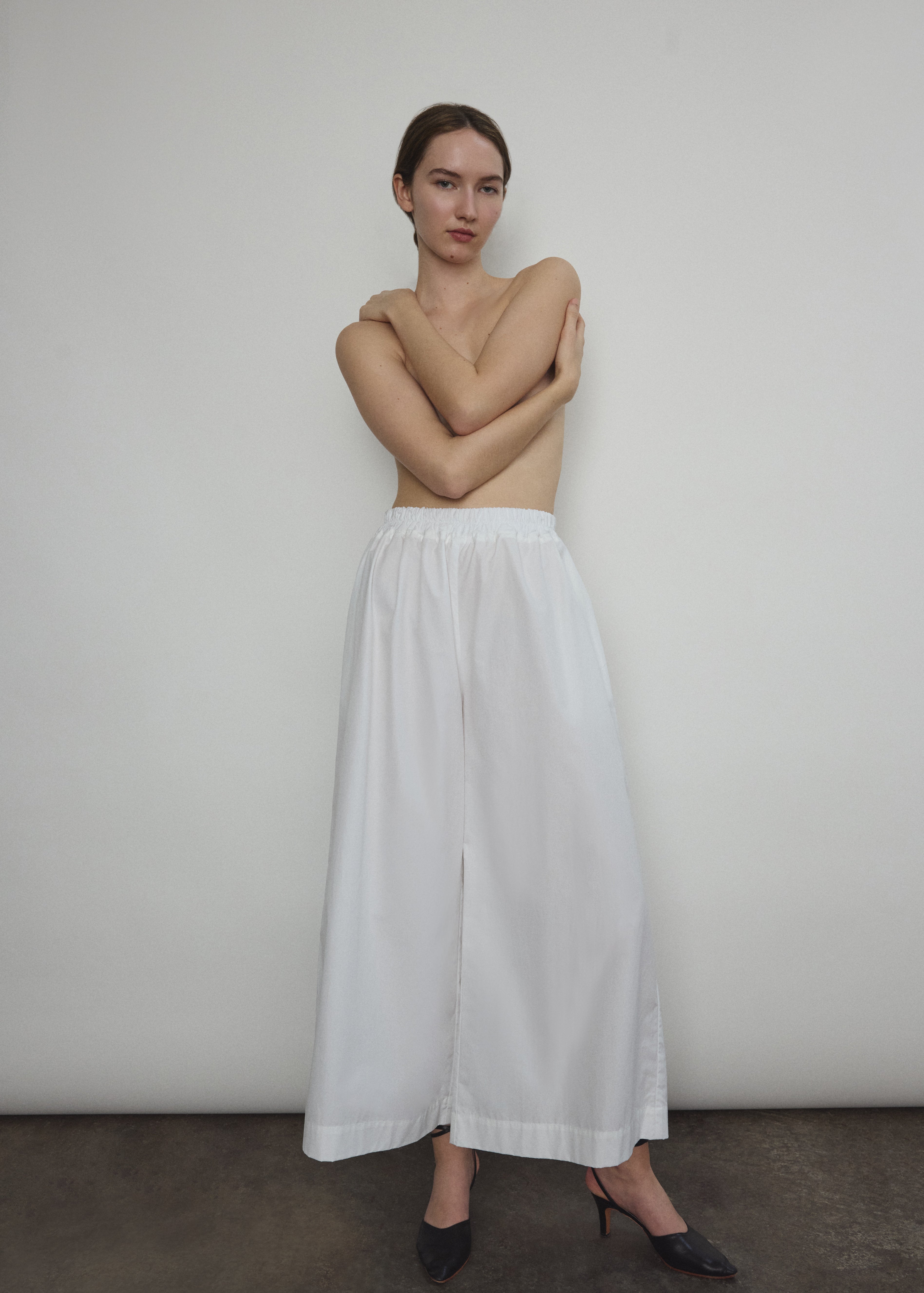 Model wearing the Kamperett Alix Pant in White, featuring a high-waisted wide-leg silhouette in crisp Japanese cotton lawn with deep side pockets.