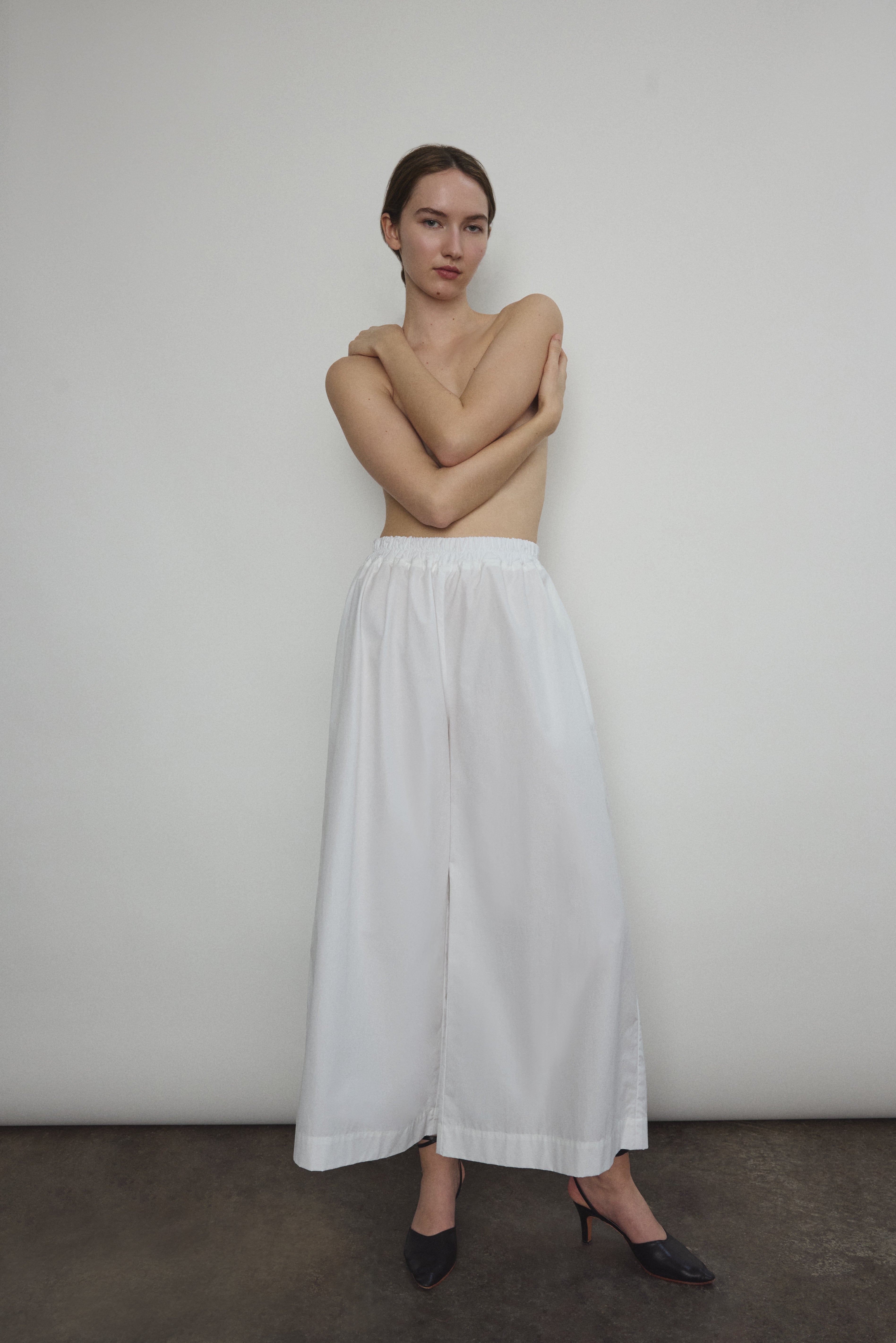 Model wearing the Kamperett Alix Pant in White, featuring a high-waisted wide-leg silhouette in crisp Japanese cotton lawn with deep side pockets.
