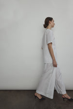 Model wearing the Kamperett Alix Pant in White, featuring a high-waisted wide-leg silhouette in crisp Japanese cotton lawn with deep side pockets.
