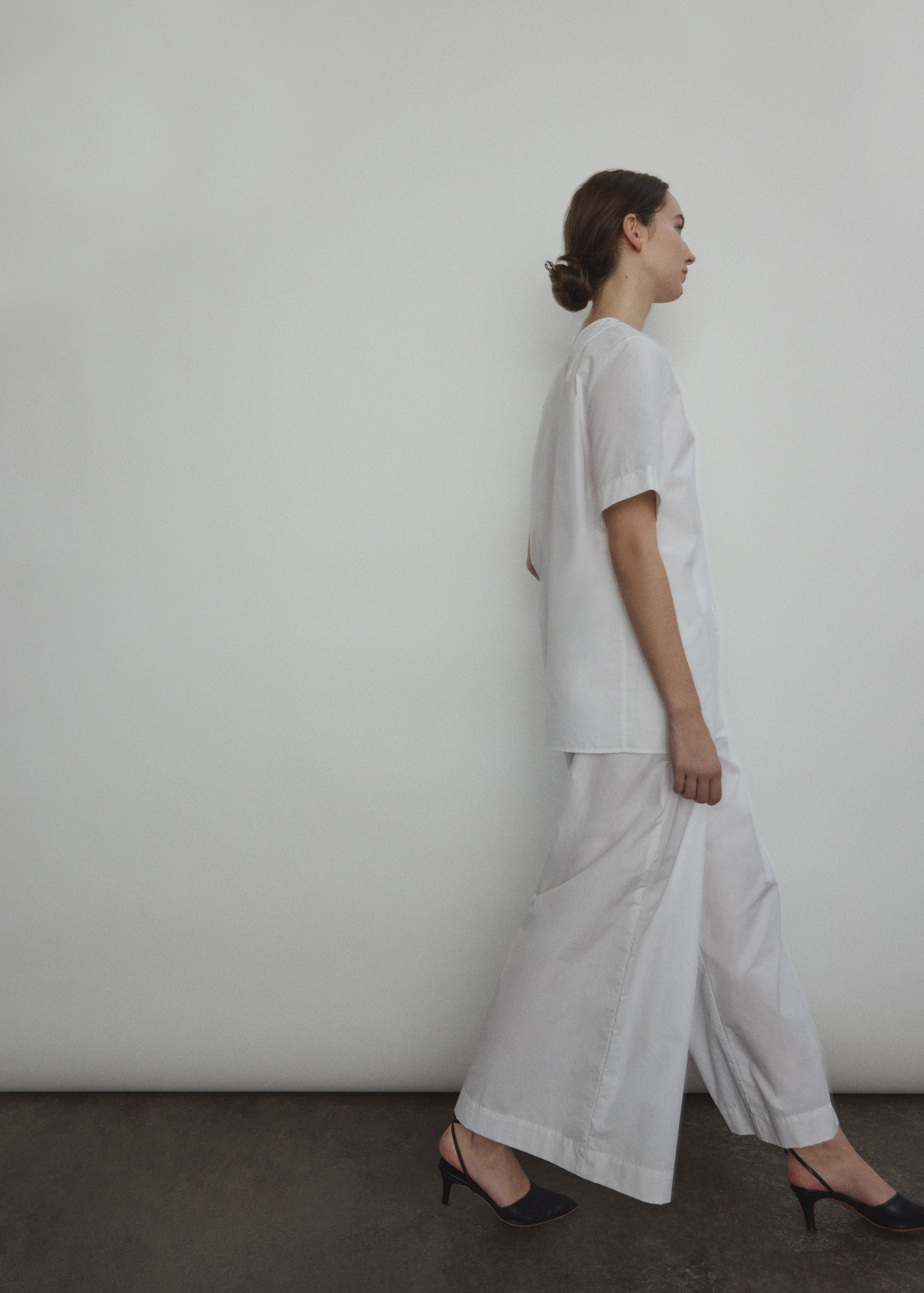 Model wearing the Kamperett Alix Pant in White, featuring a high-waisted wide-leg silhouette in crisp Japanese cotton lawn with deep side pockets.