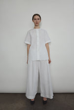 Model wearing the Kamperett Alix Pant in White, featuring a high-waisted wide-leg silhouette in crisp Japanese cotton lawn with deep side pockets.