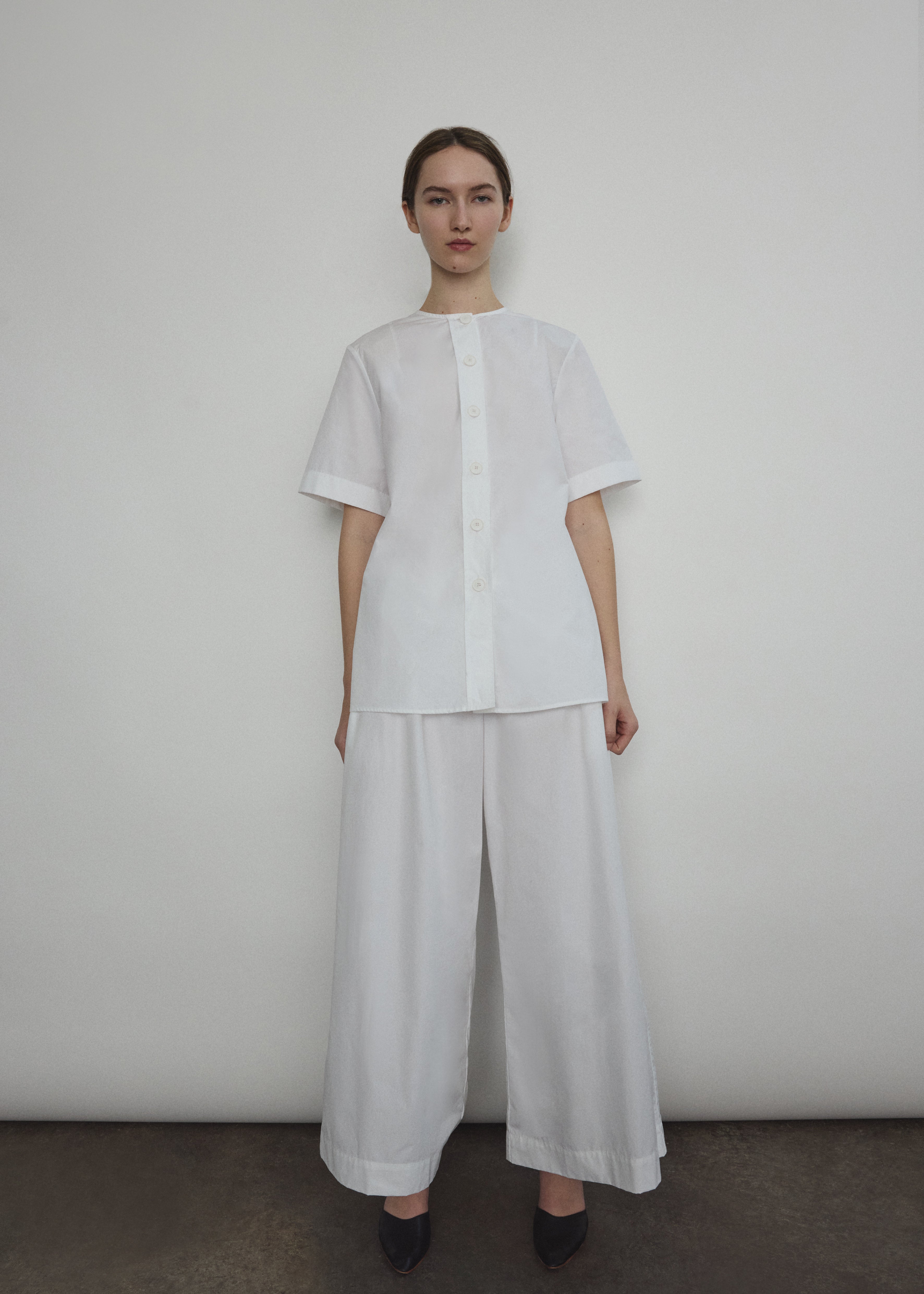 Model wearing the Kamperett Alix Pant in White, featuring a high-waisted wide-leg silhouette in crisp Japanese cotton lawn with deep side pockets.