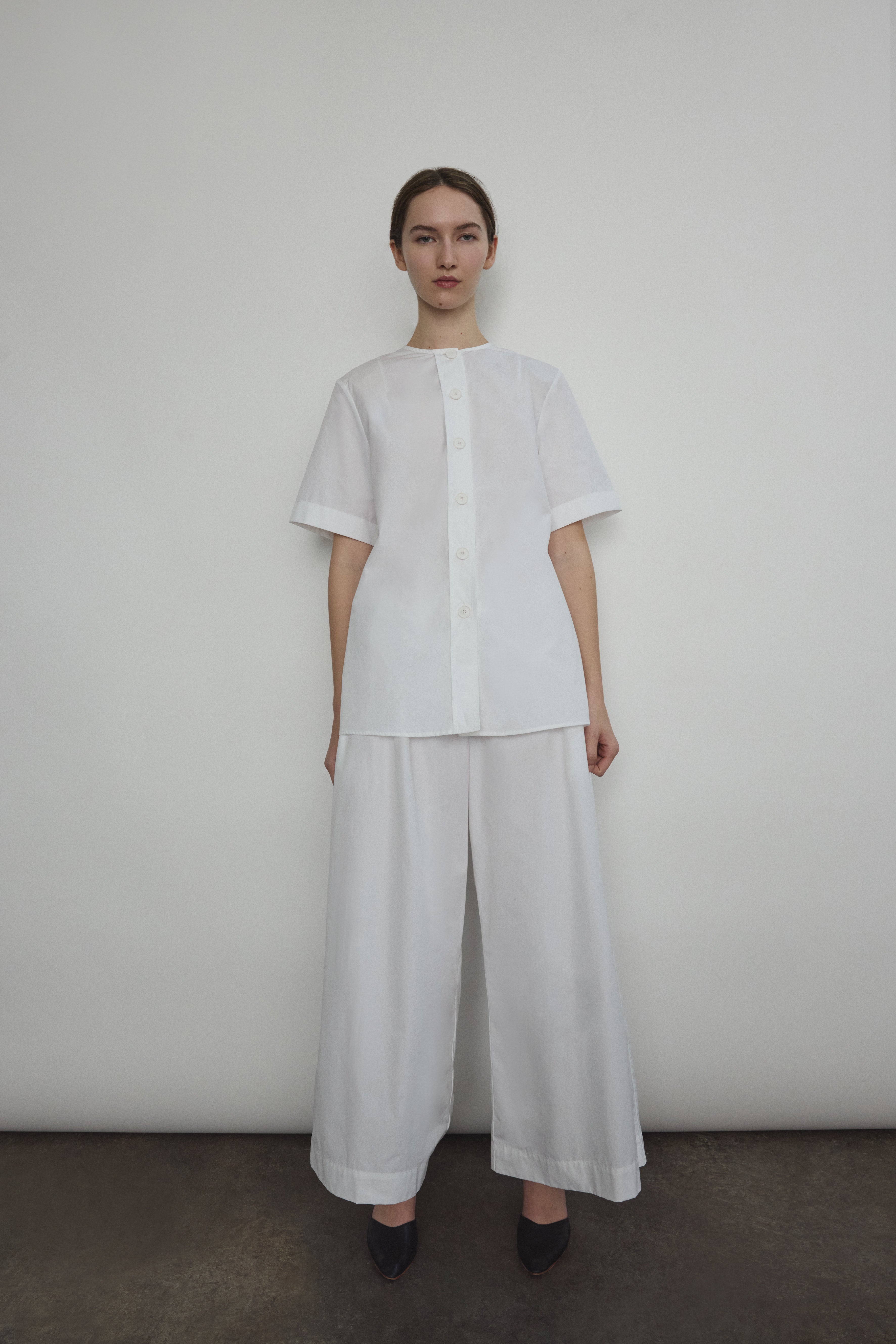 Model wearing the Kamperett Alix Pant in White, featuring a high-waisted wide-leg silhouette in crisp Japanese cotton lawn with deep side pockets.