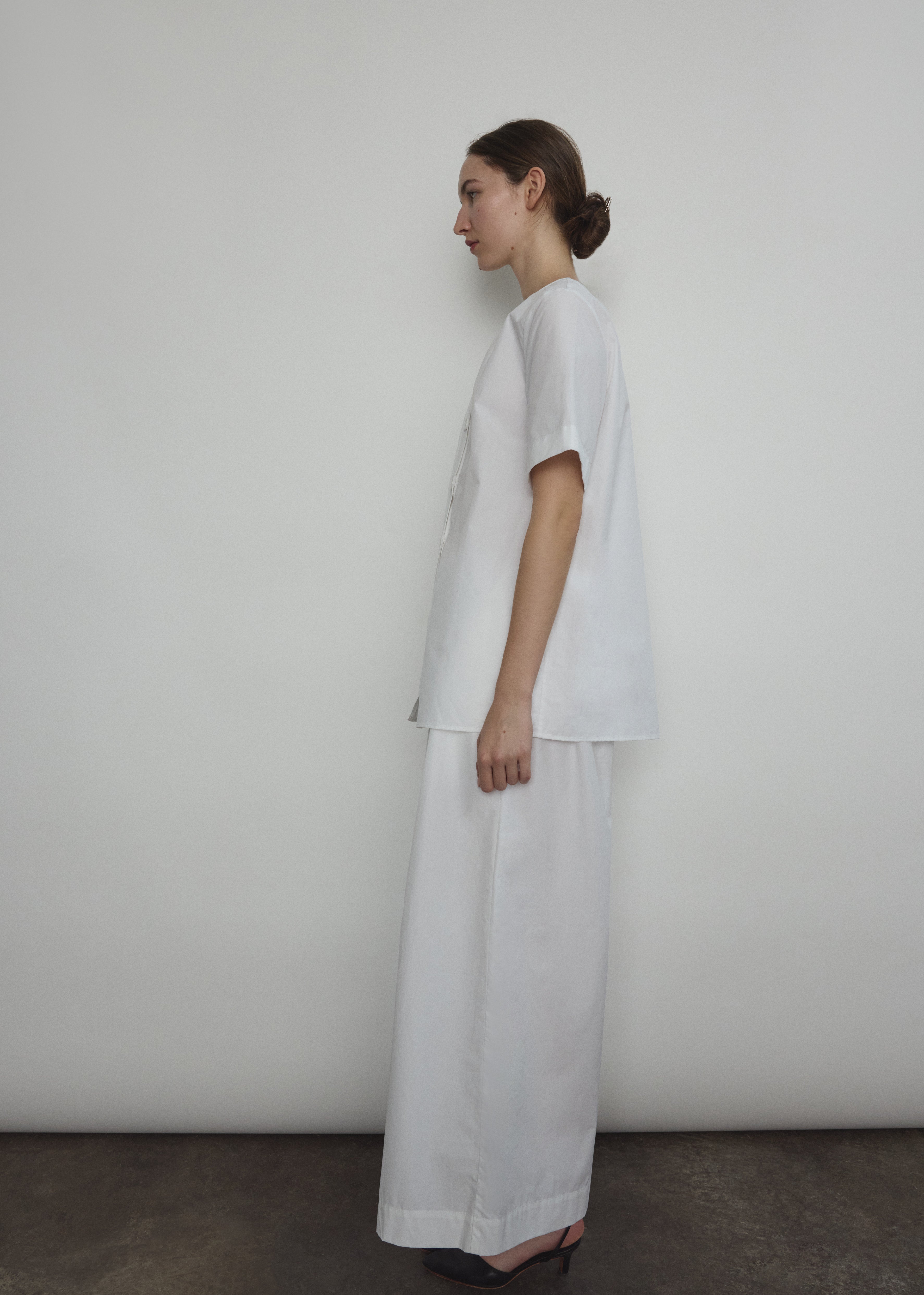 Model wearing the Kamperett Alix Pant in White, featuring a high-waisted wide-leg silhouette in crisp Japanese cotton lawn with deep side pockets.