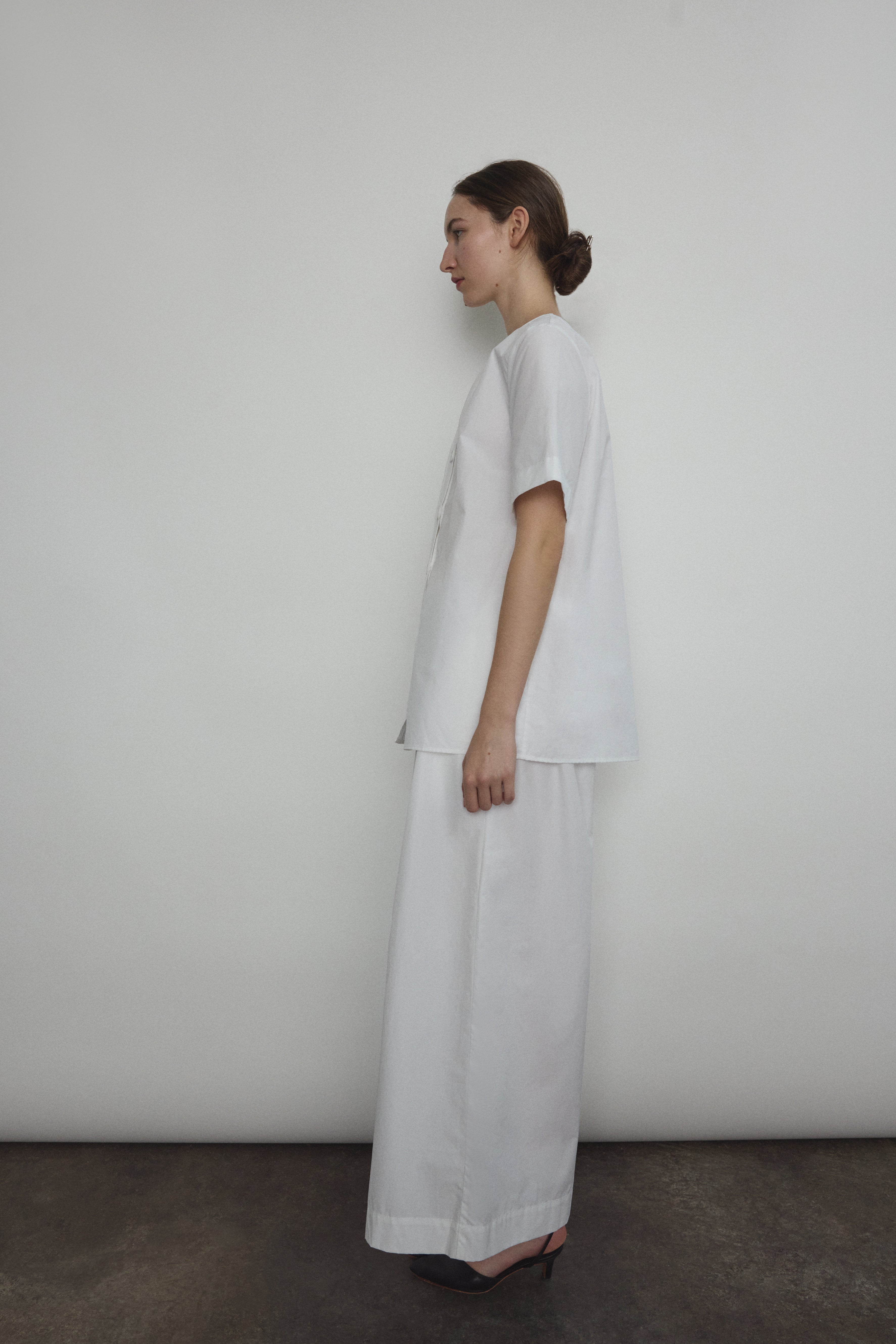 Model wearing the Kamperett Alix Pant in White, featuring a high-waisted wide-leg silhouette in crisp Japanese cotton lawn with deep side pockets.