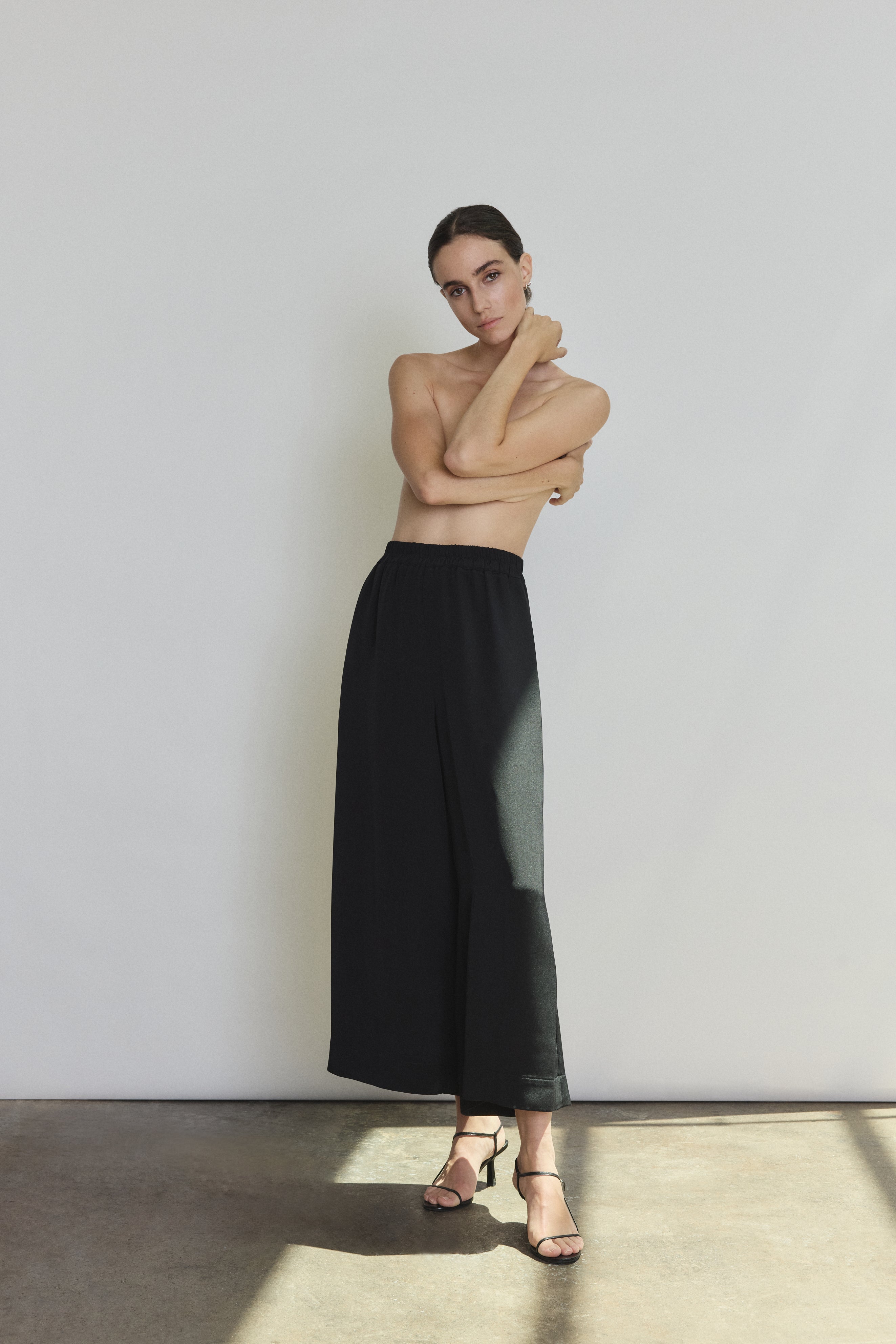 Front view of a model wearing the black silk crepe Kamperett Alix Silk Crepe Pant, a wide-leg pull-on pant with elastic waistband.