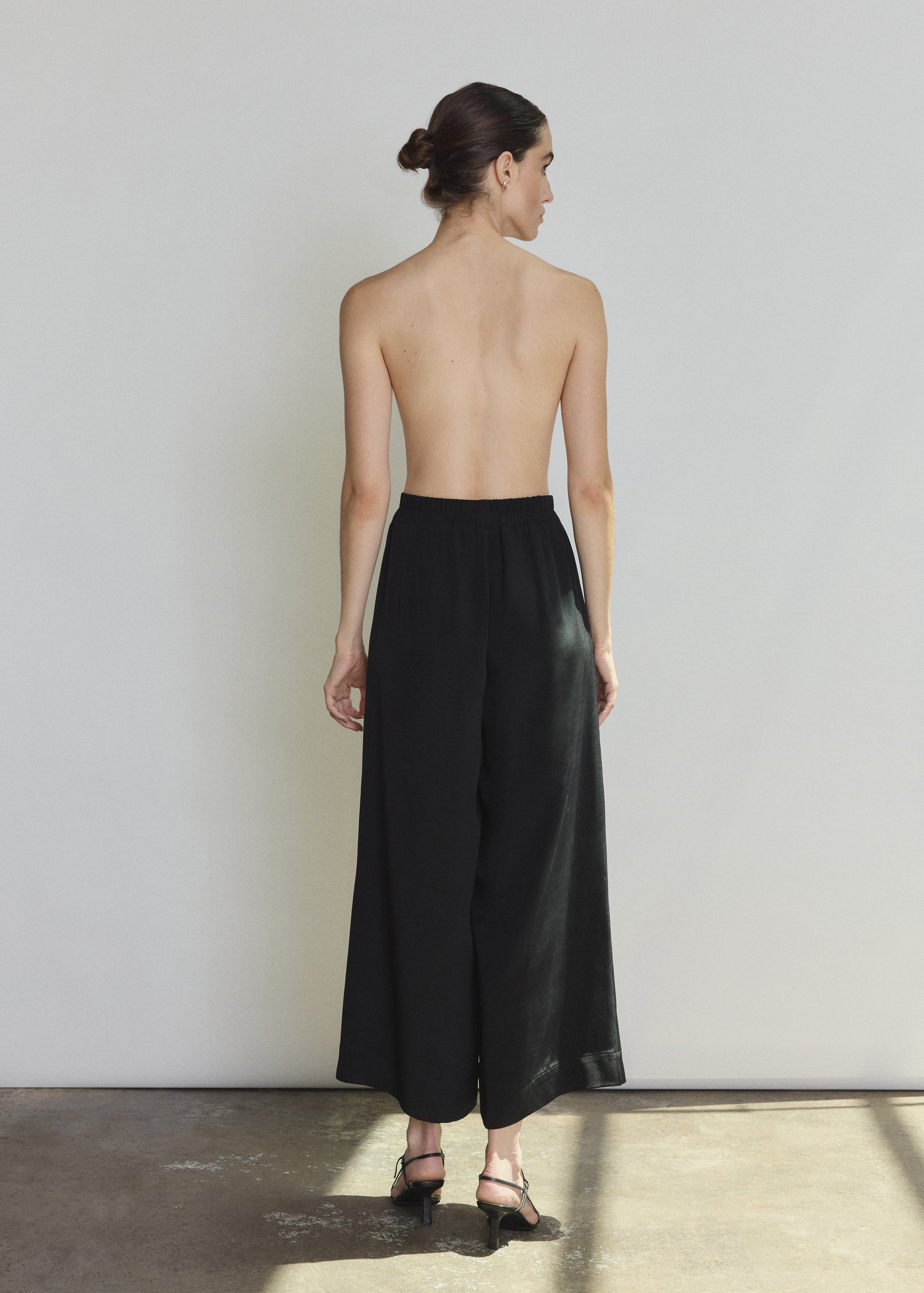 Side view of the black silk crepe Kamperett Alix Silk Crepe Pant showing the wide-leg silhouette and inseam pockets.