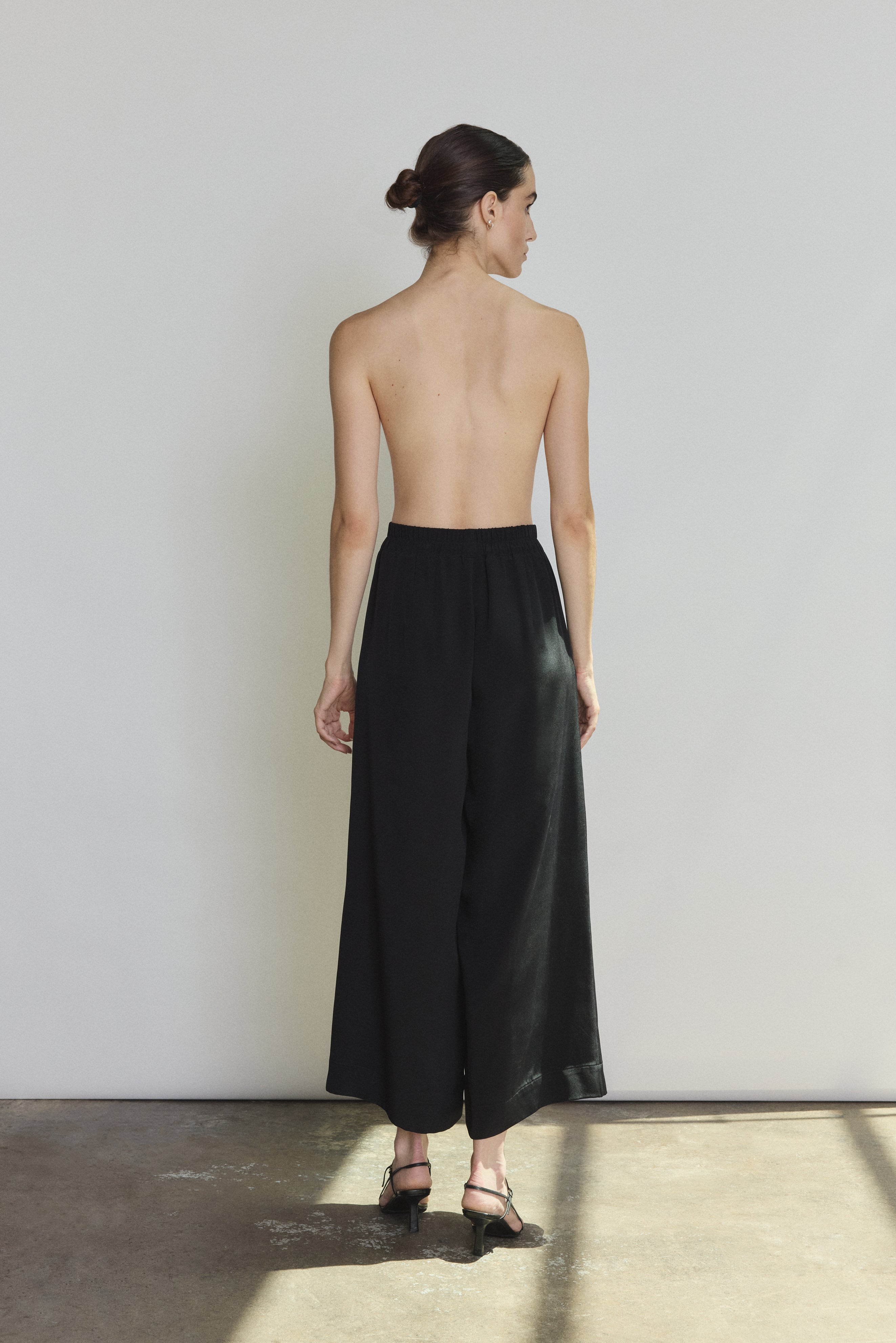 Side view of the black silk crepe Kamperett Alix Silk Crepe Pant showing the wide-leg silhouette and inseam pockets.