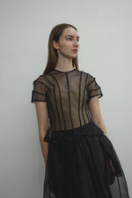 Model wearing the Kamperett Anemoia Blouse in Black silk organza, highlighting the voluminous sculptural sleeves and elegant mock neck silhouette.