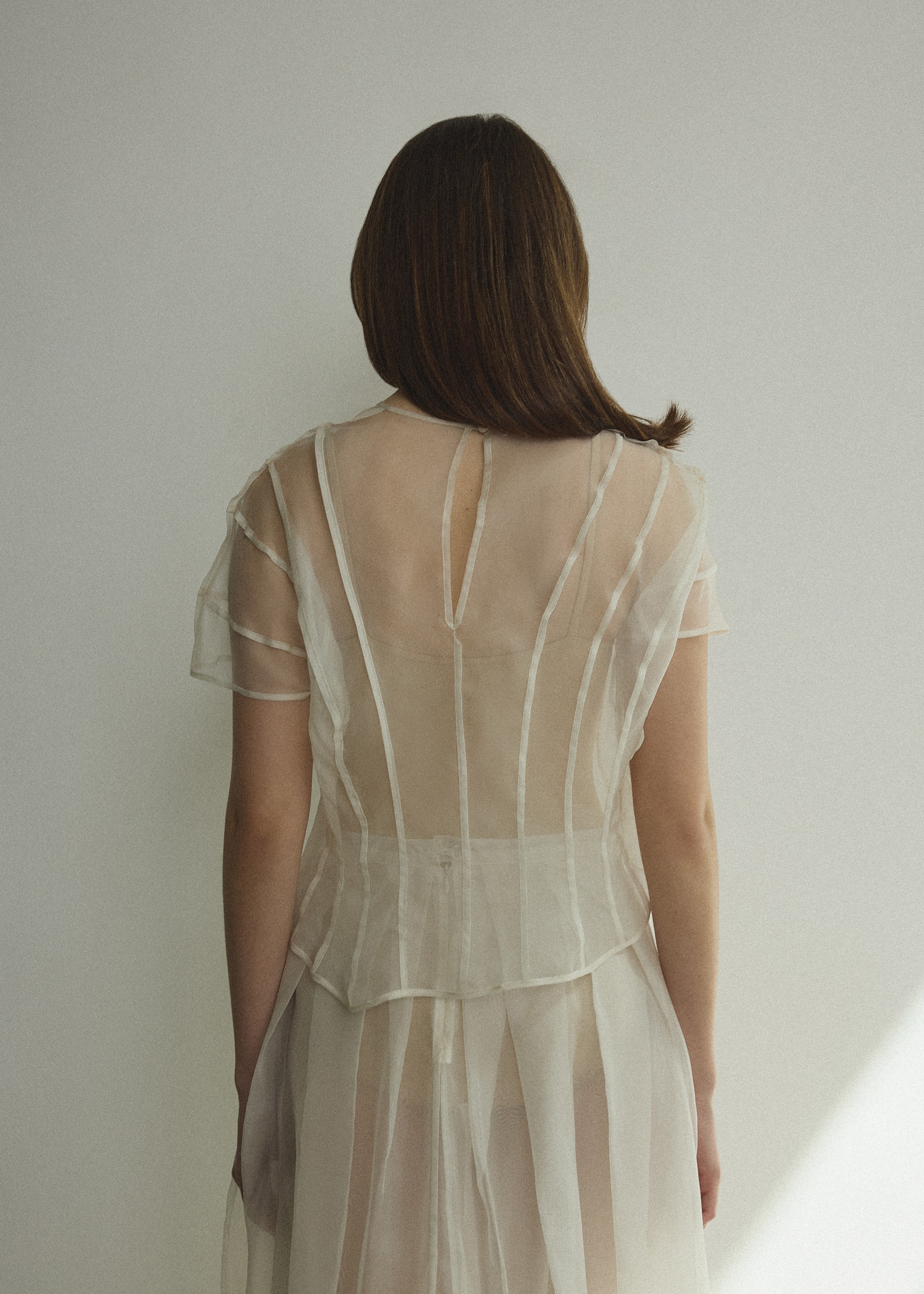 Model wearing the Kamperett Anemoia Blouse in Ivory silk organza, highlighting the voluminous sculptural sleeves and elegant mock neck silhouette.