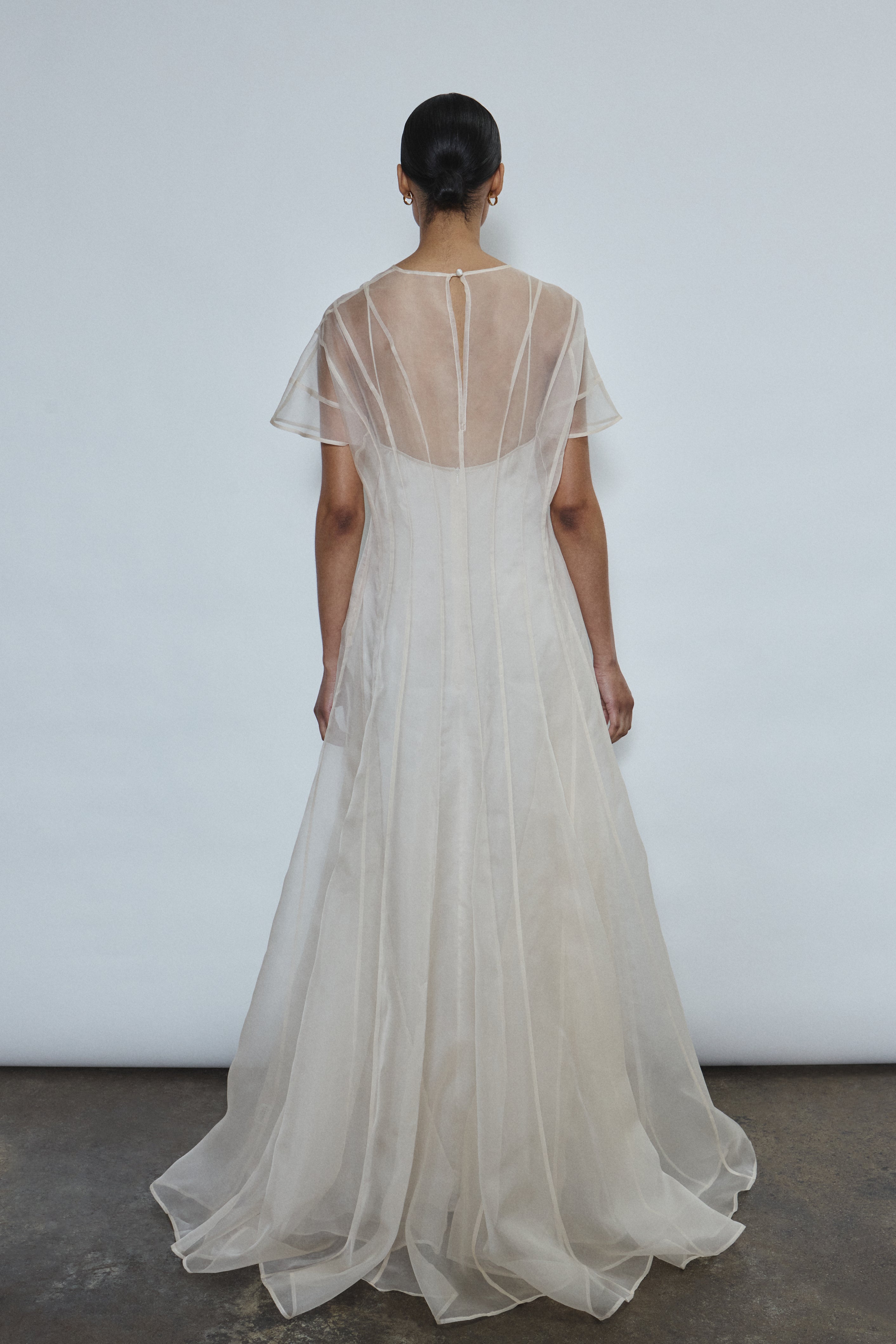Model wearing the voluminous Kamperett Anemoia Gown in Ivory silk organza, featuring architectural French seams and a graceful floor-length silhouette.