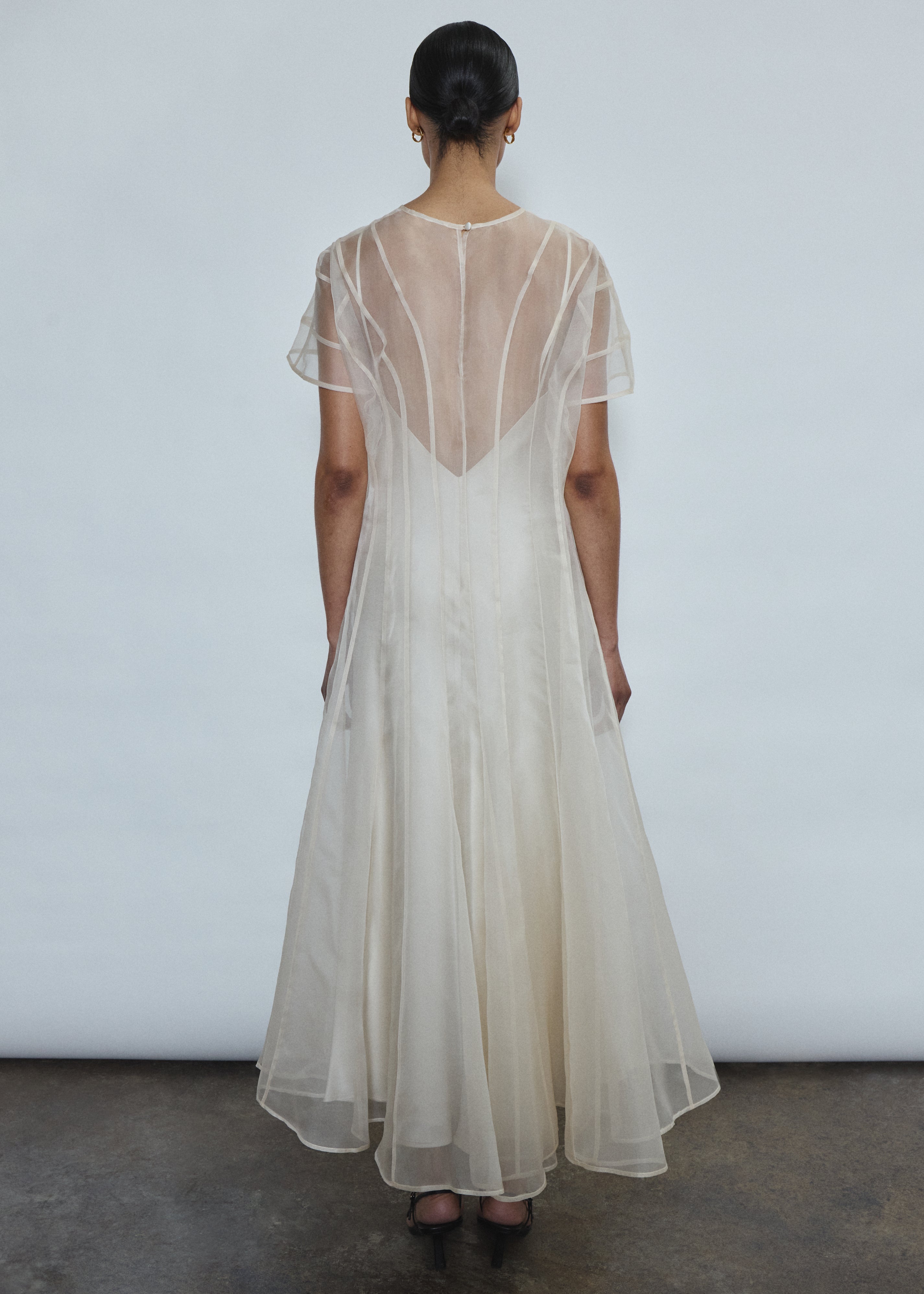 Model wearing the voluminous Kamperett Anemoia Midi dress in Ivory silk organza, highlighting the architectural French seams and graceful midi-length silhouette.