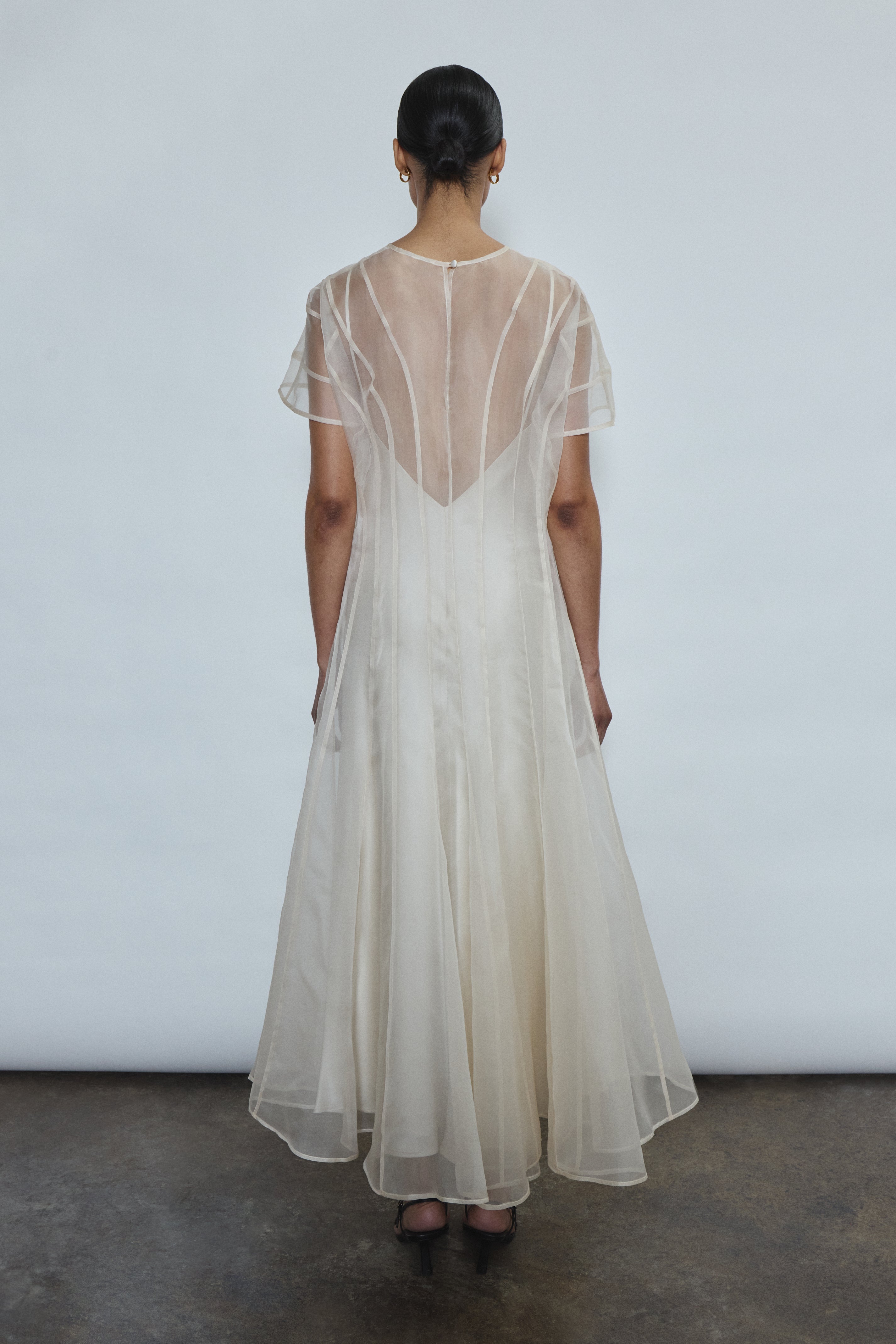 Model wearing the voluminous Kamperett Anemoia Midi dress in Ivory silk organza, highlighting the architectural French seams and graceful midi-length silhouette.