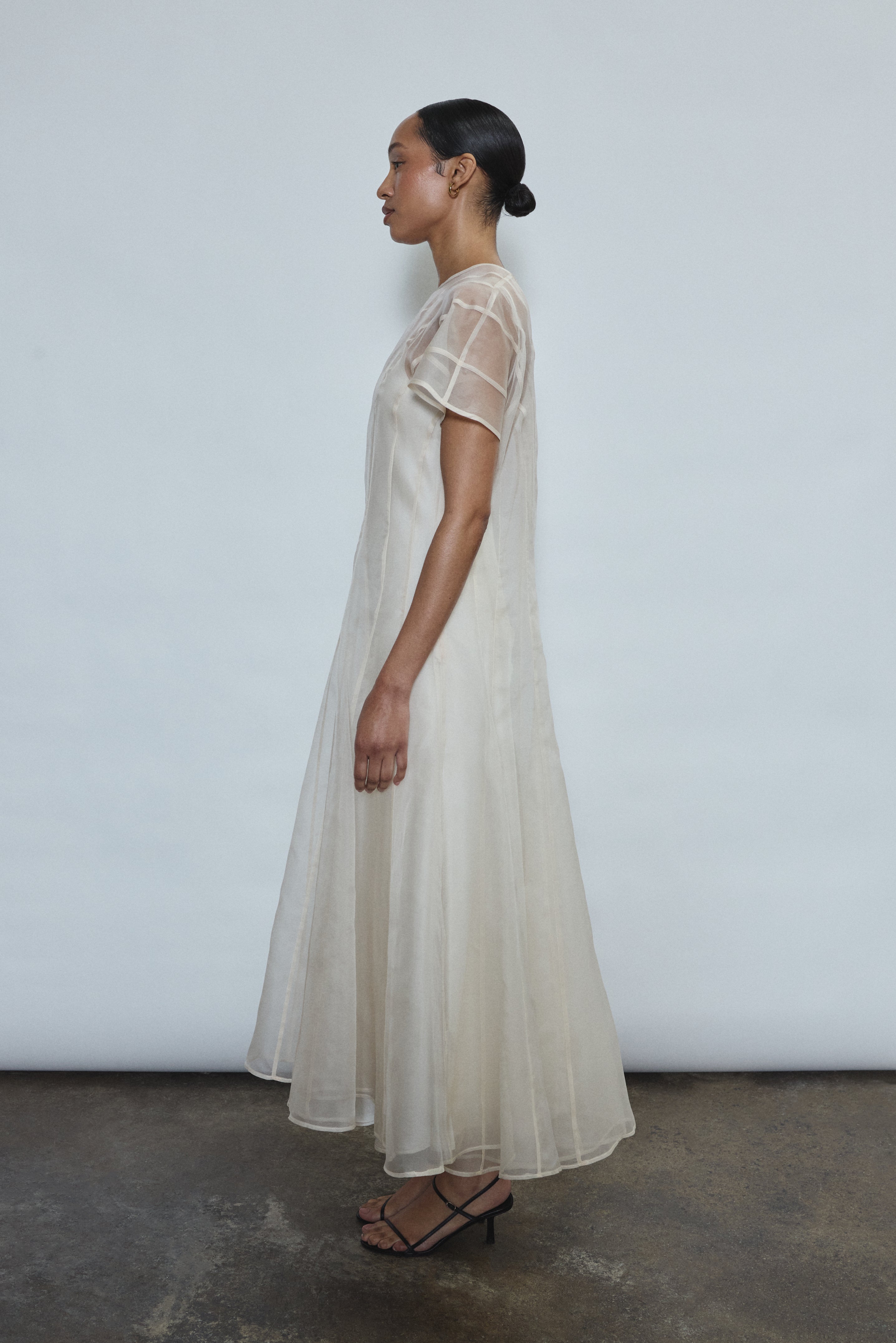 Model wearing the voluminous Kamperett Anemoia Midi dress in Ivory silk organza, highlighting the architectural French seams and graceful midi-length silhouette.